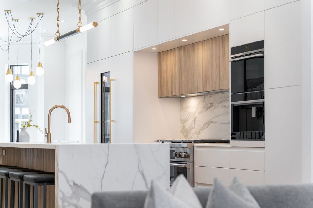 Modern white kitchen interior with wooden cabinets, pendant lights, and sleek appliances showcases contemporary design.