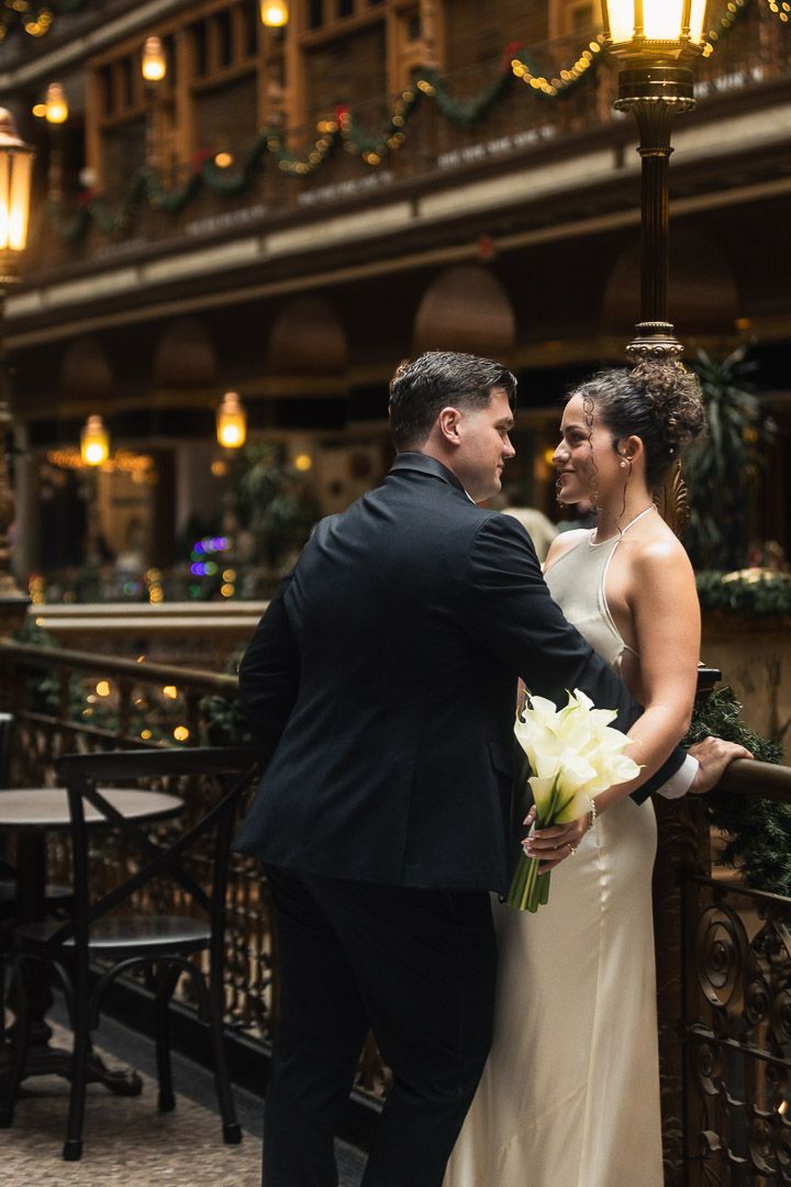 A couple on their wedding day shares an intimate moment under warm lighting in the ornate historic Arcade building.
