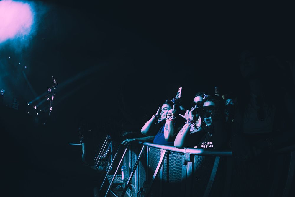 Excited concert crowd cheering under blue stage lights at a live music event.