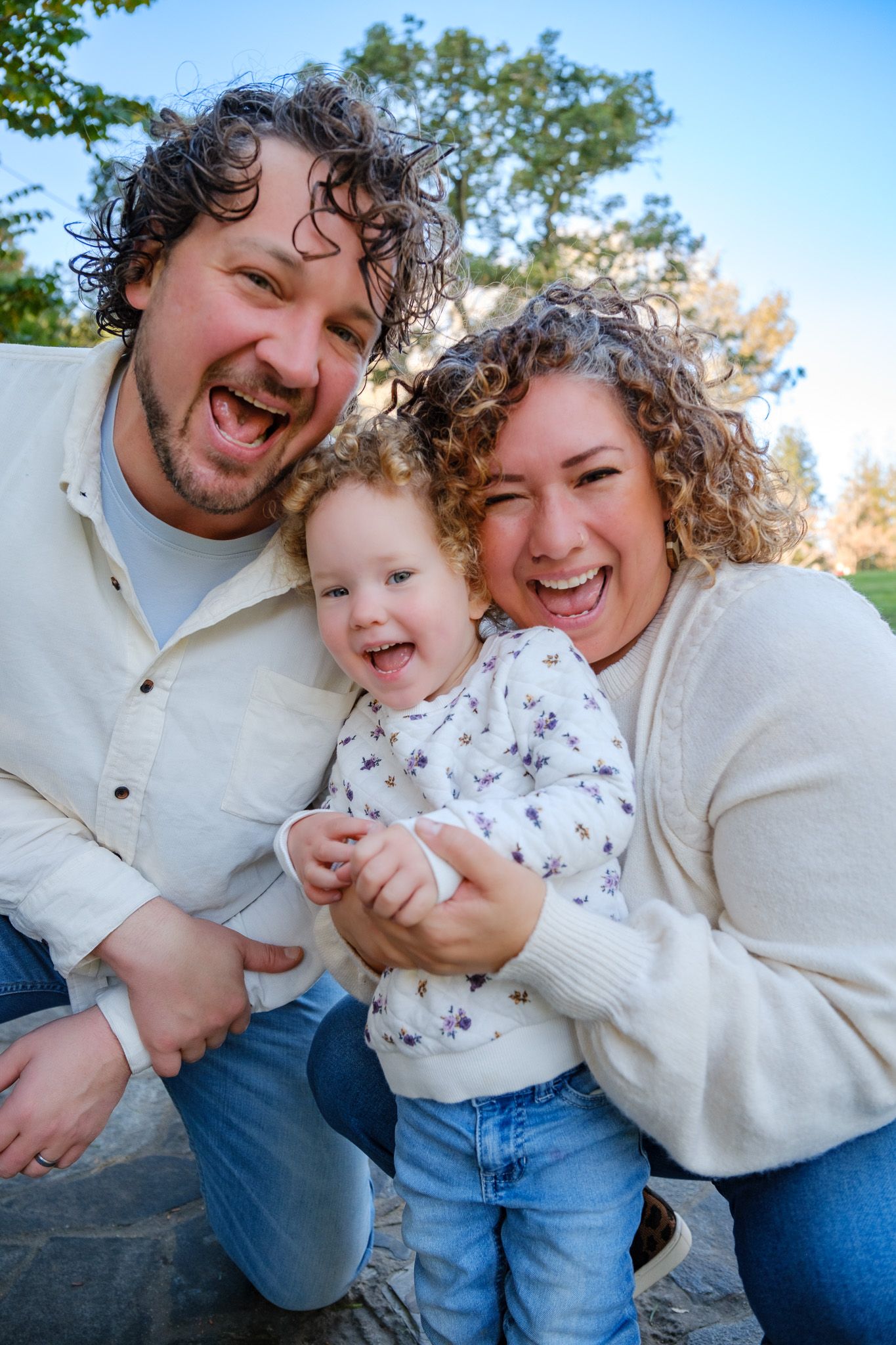 Black and white photo of a man smiling with two young girls in a park setting.