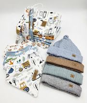 Baby gift set with construction-themed bibs, muslin cloths, and stacked knit beanies in blue, brown, and sage green.