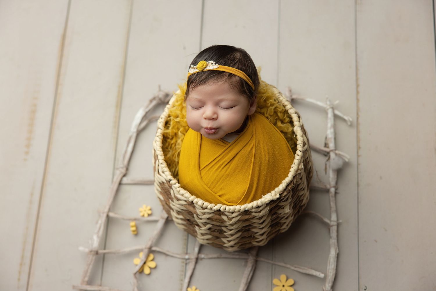 Peaceful newborn baby swaddled in cream wrap sleeping on soft beige blanket during professional newborn photography session.