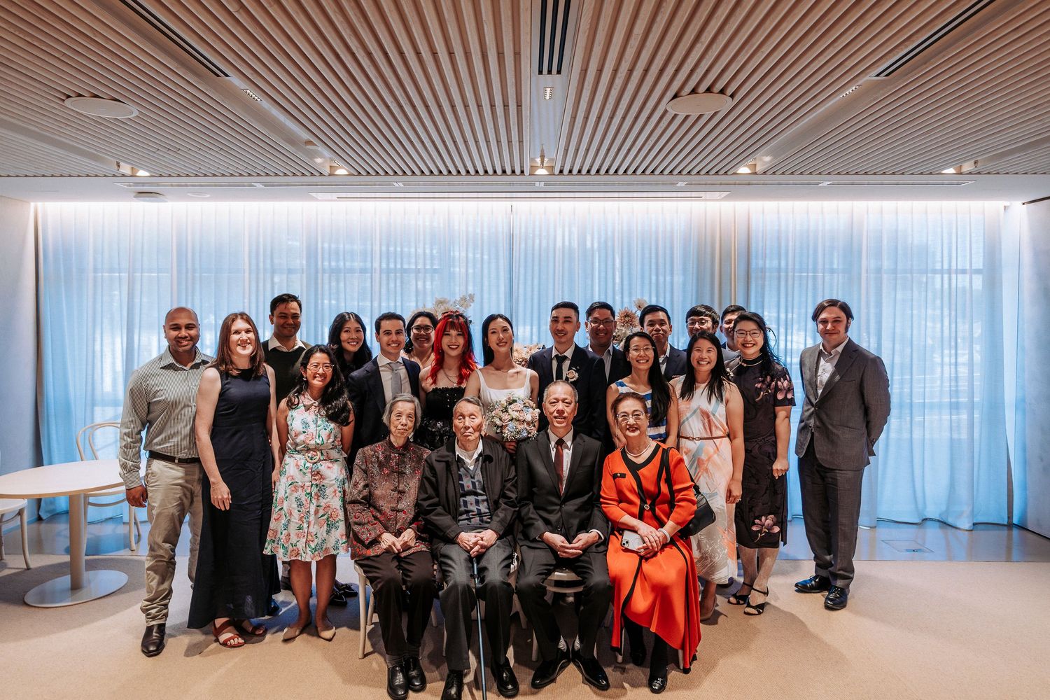 Large group portrait of diverse professionals posing together in a modern office with elegant decor.