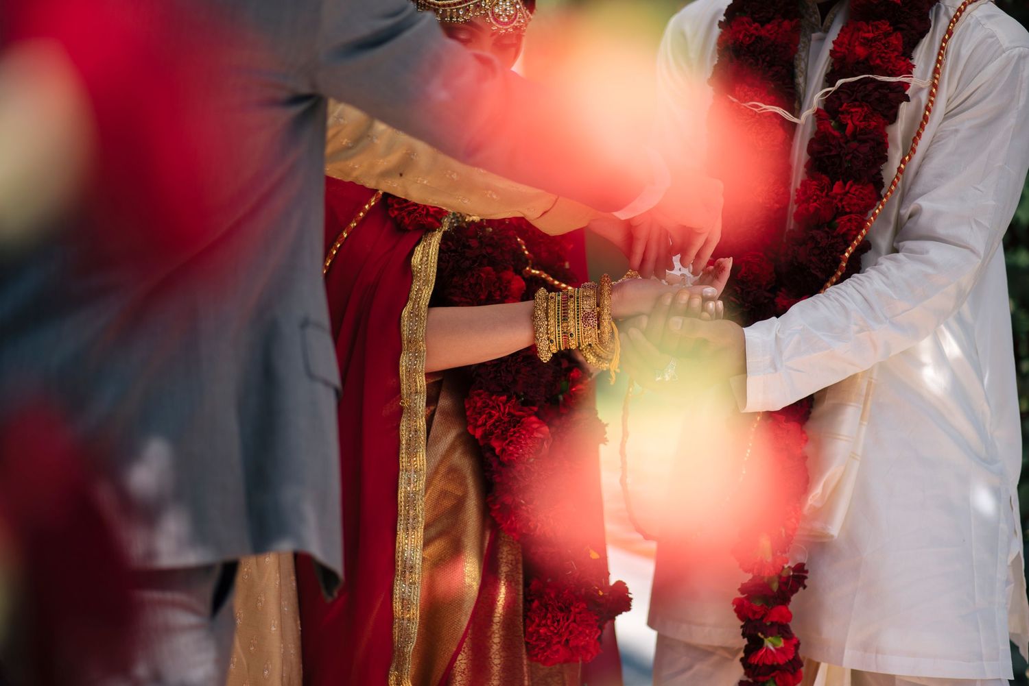 Indian wedding ceremony couple exchanging garlands in traditional red and white attire with floral decorations.