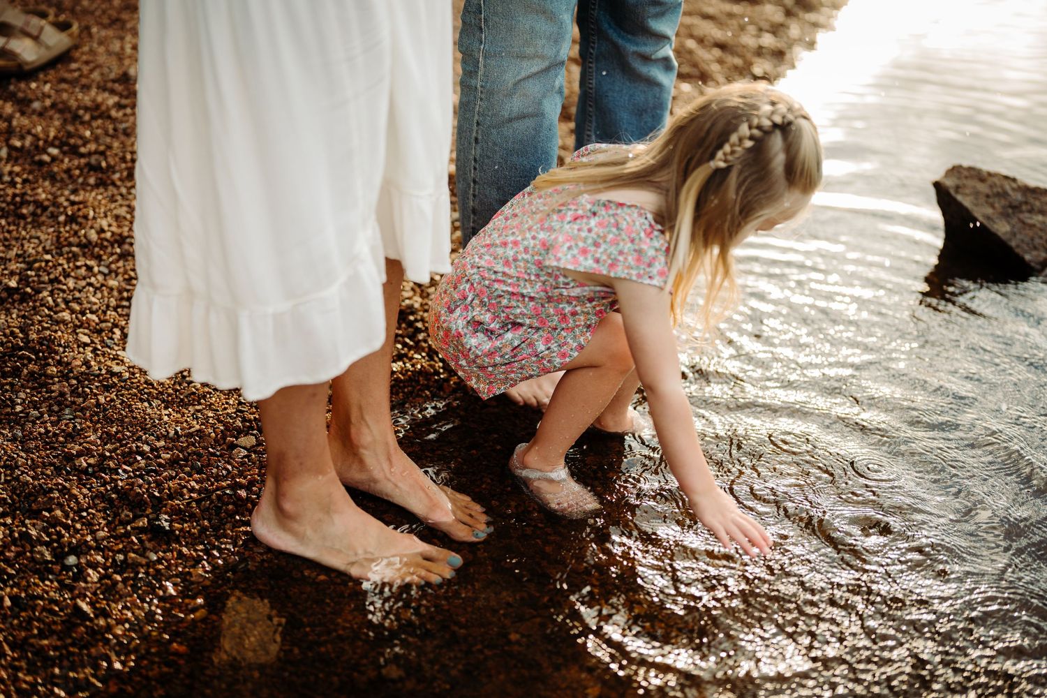 family dips feet in the water during storytelling photography session