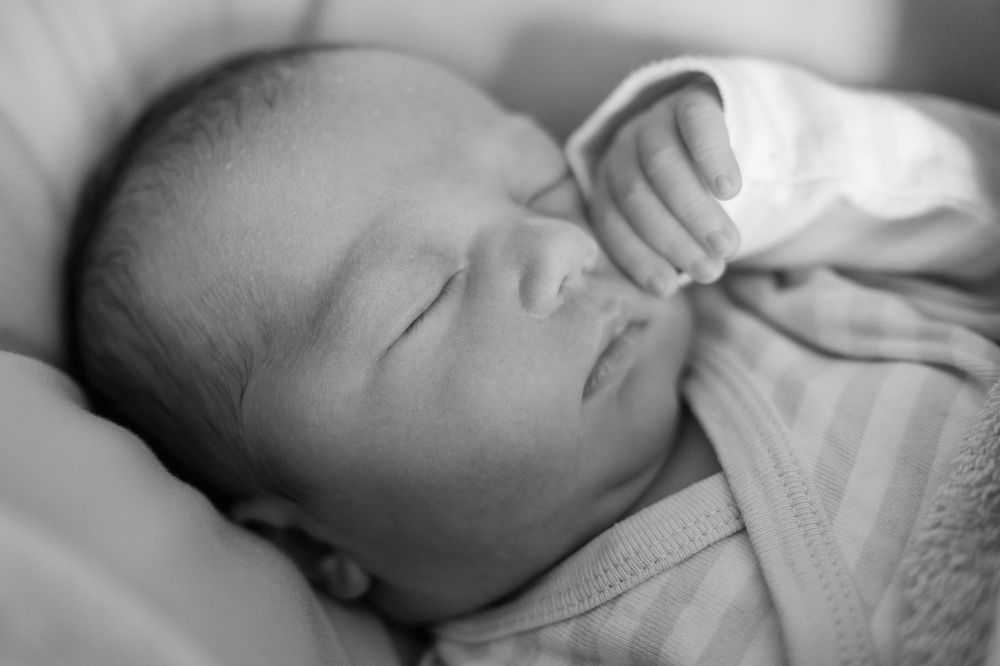 Un portrait paisible en noir et blanc d'un nouveau-né endormi emmailloté dans un tissu doux.