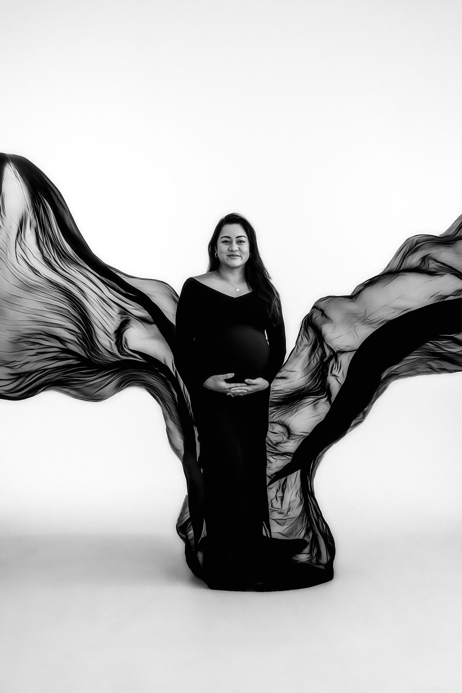 Pregnant woman in black flowing gown with dramatic fabric wings, black and white photo by Atlanta maternity photographer