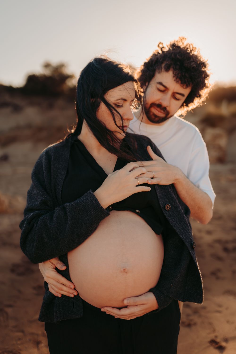 Pareja esperando a su bebé durante una sesión de fotografía de embarazo al atardecer en Girona.