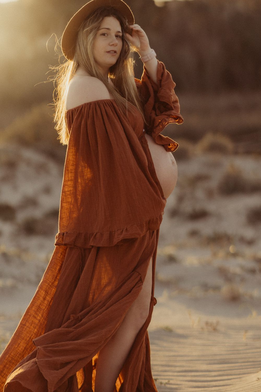 Futura mamá con vestido de maternidad durante una sesión de fotografía de embarazo al atardecer en Girona.