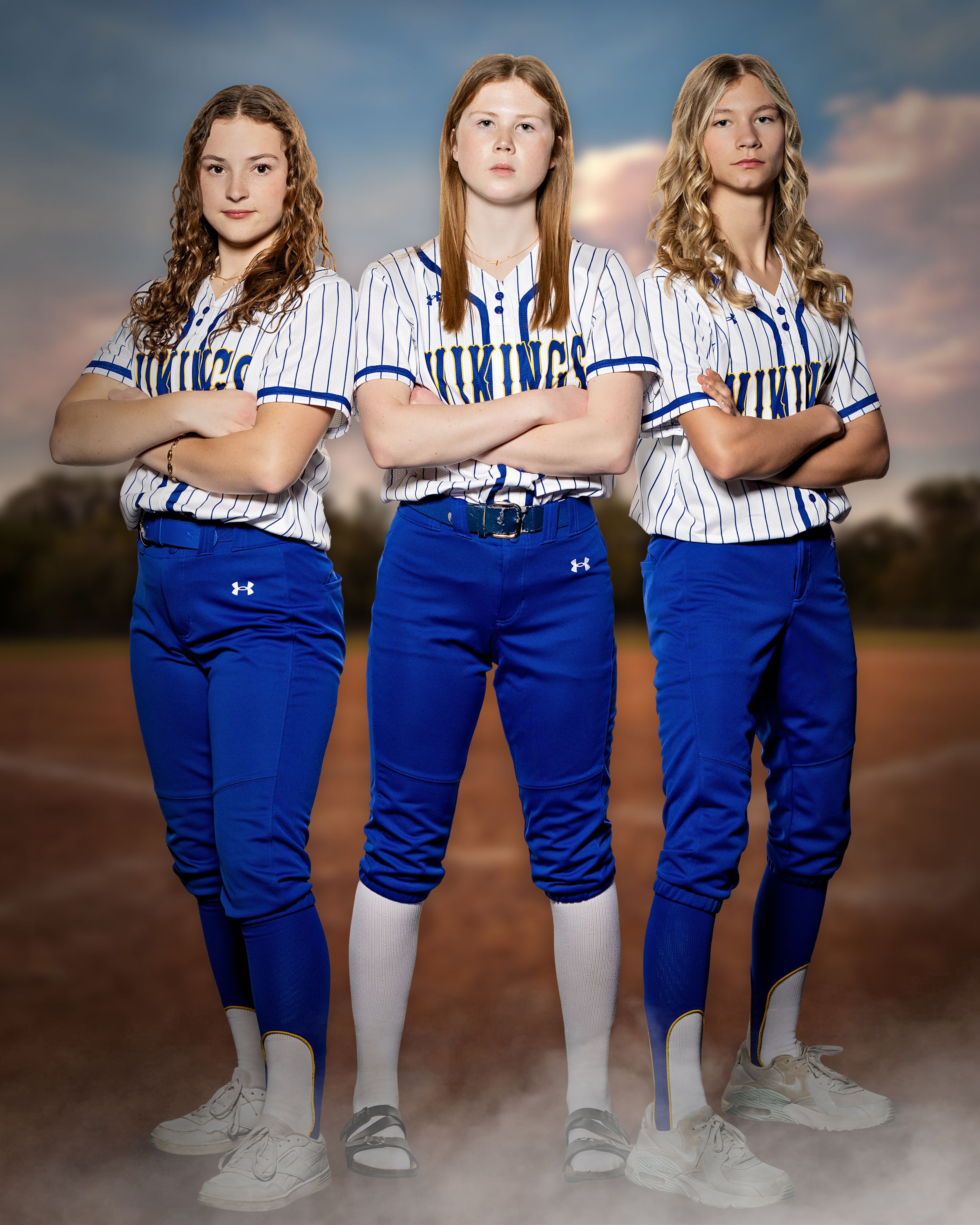 Three Minneota Vikings softball players in blue and white pinstripe uniforms posing together.
