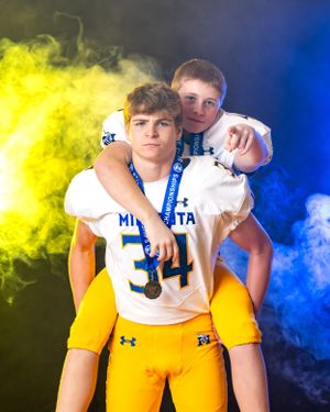 Two Minneota Vikings football players posing together with medals in blue and gold uniforms.