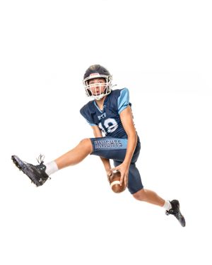 Young football player in blue Knights jersey number 19 leaping mid-air while carrying the ball.