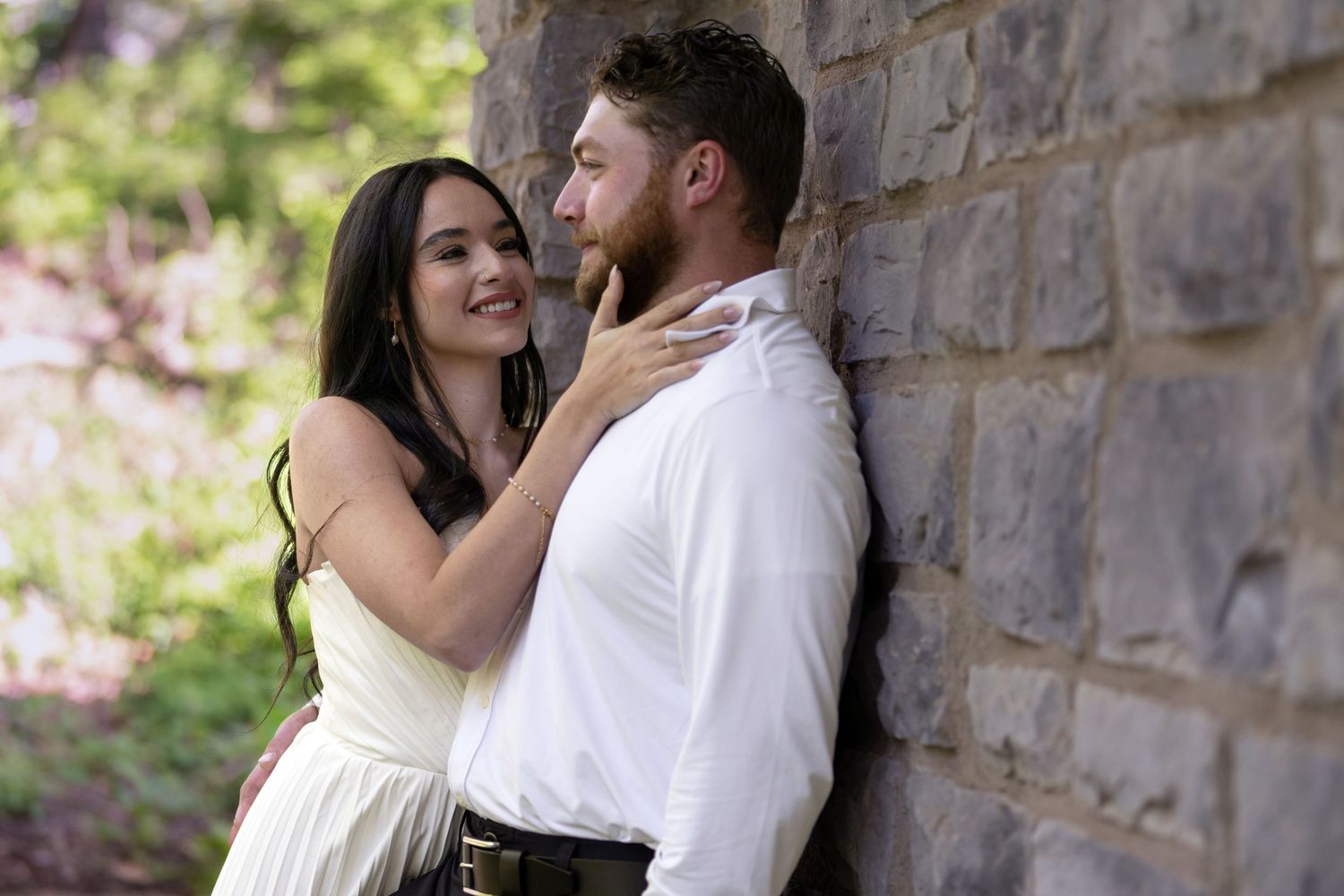 Romantic couple embracing by a stone wall outdoors Jeffrey Mansion for their Engagement Session
