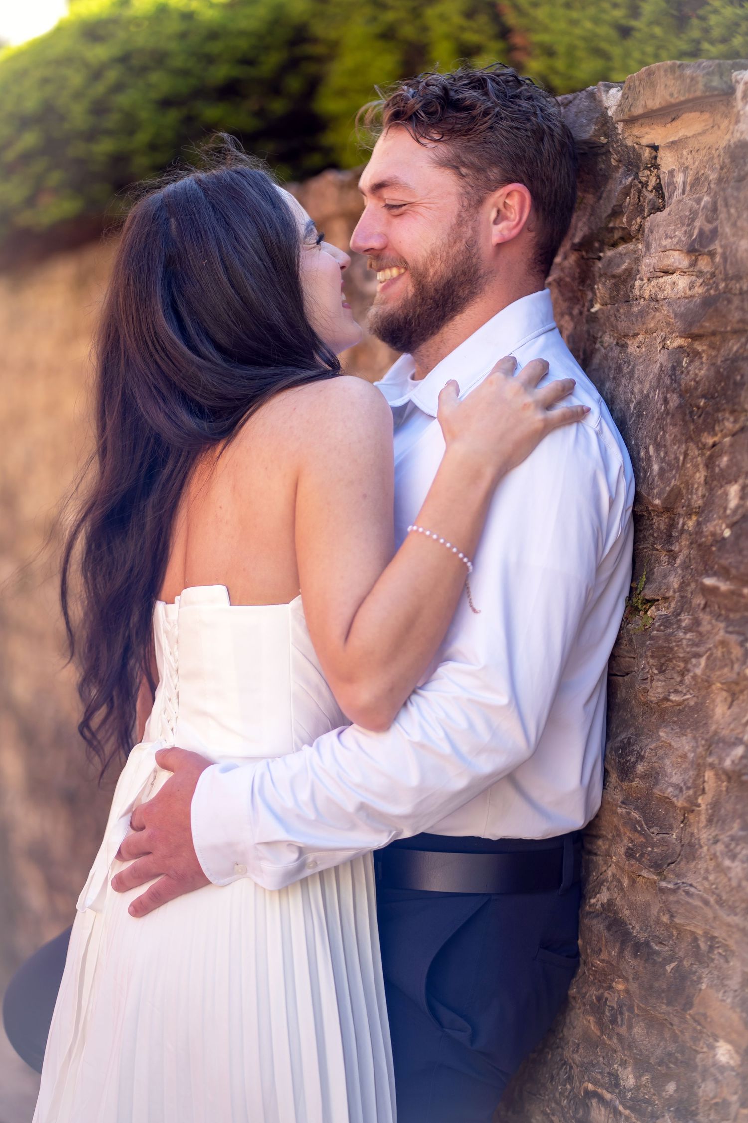 Romantic couple embracing near a stone wall outdoor Jeffrey Mansion Engagement Session photo