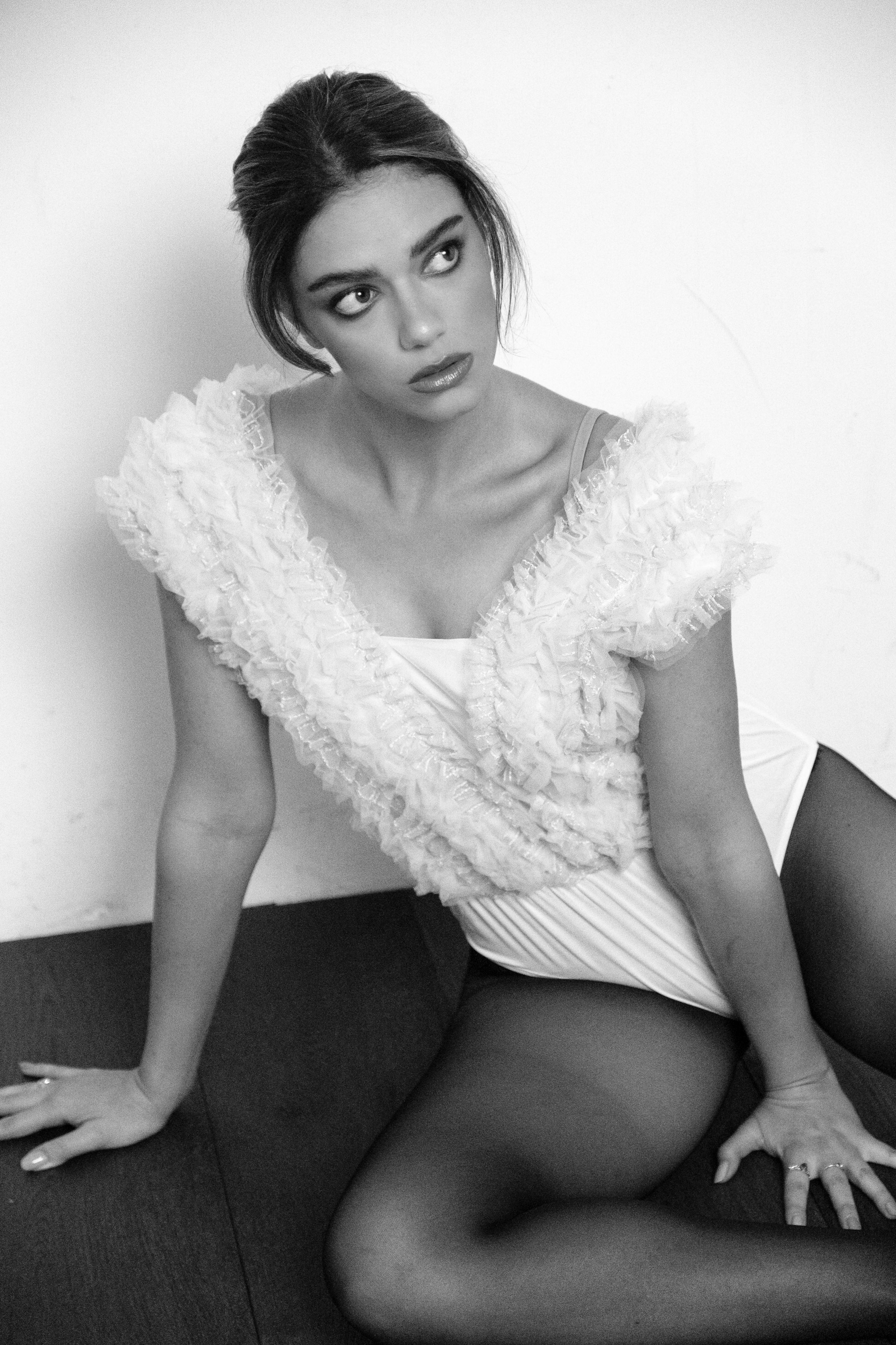Artistic black and white portrait series showing a white lace top against dark background.