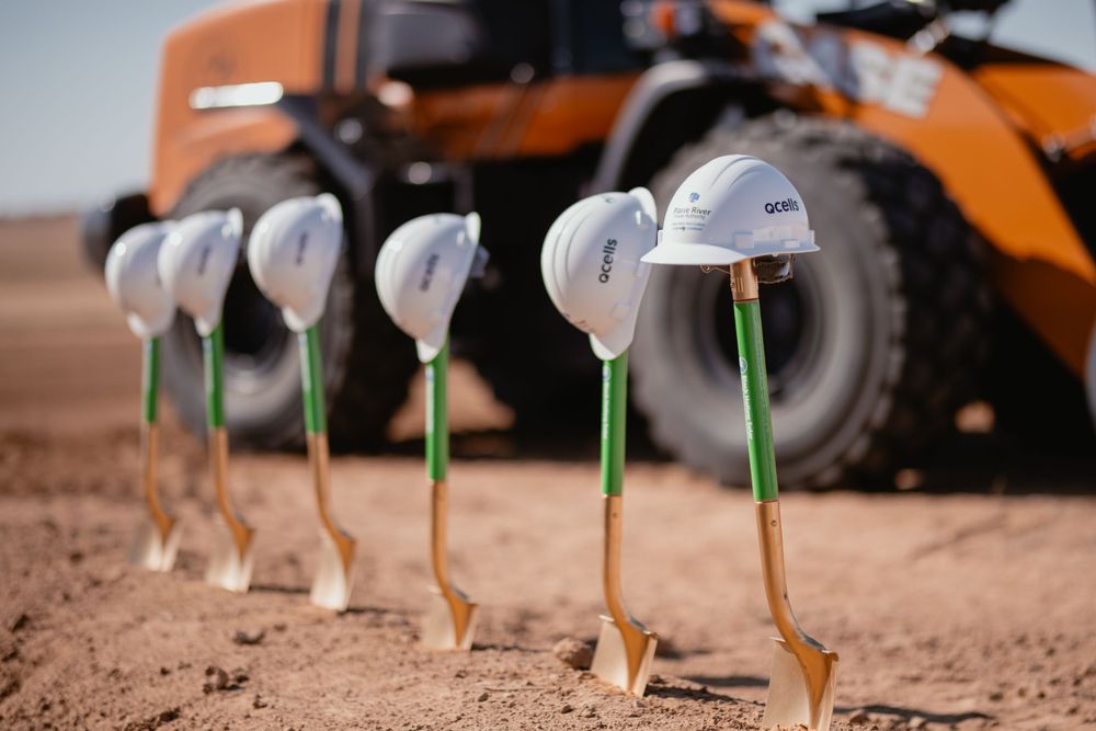 Row of ceremonial white hard hats on shovels at groundbreaking event.