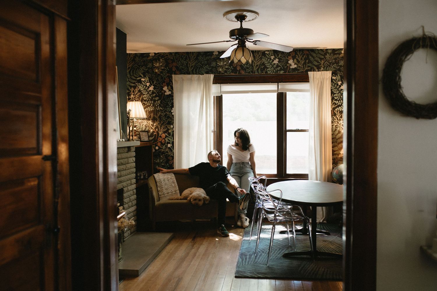 View through doorway of a cozy room with floral wallpaper, vintage furniture, and warm lighting.