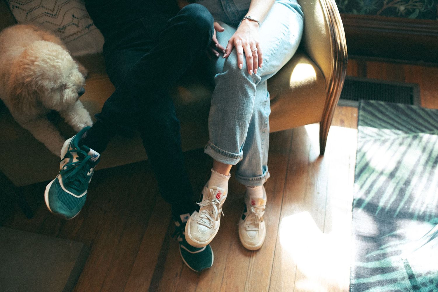Low angle shot of casual footwear and jeans in sunlit room with hardwood floors.