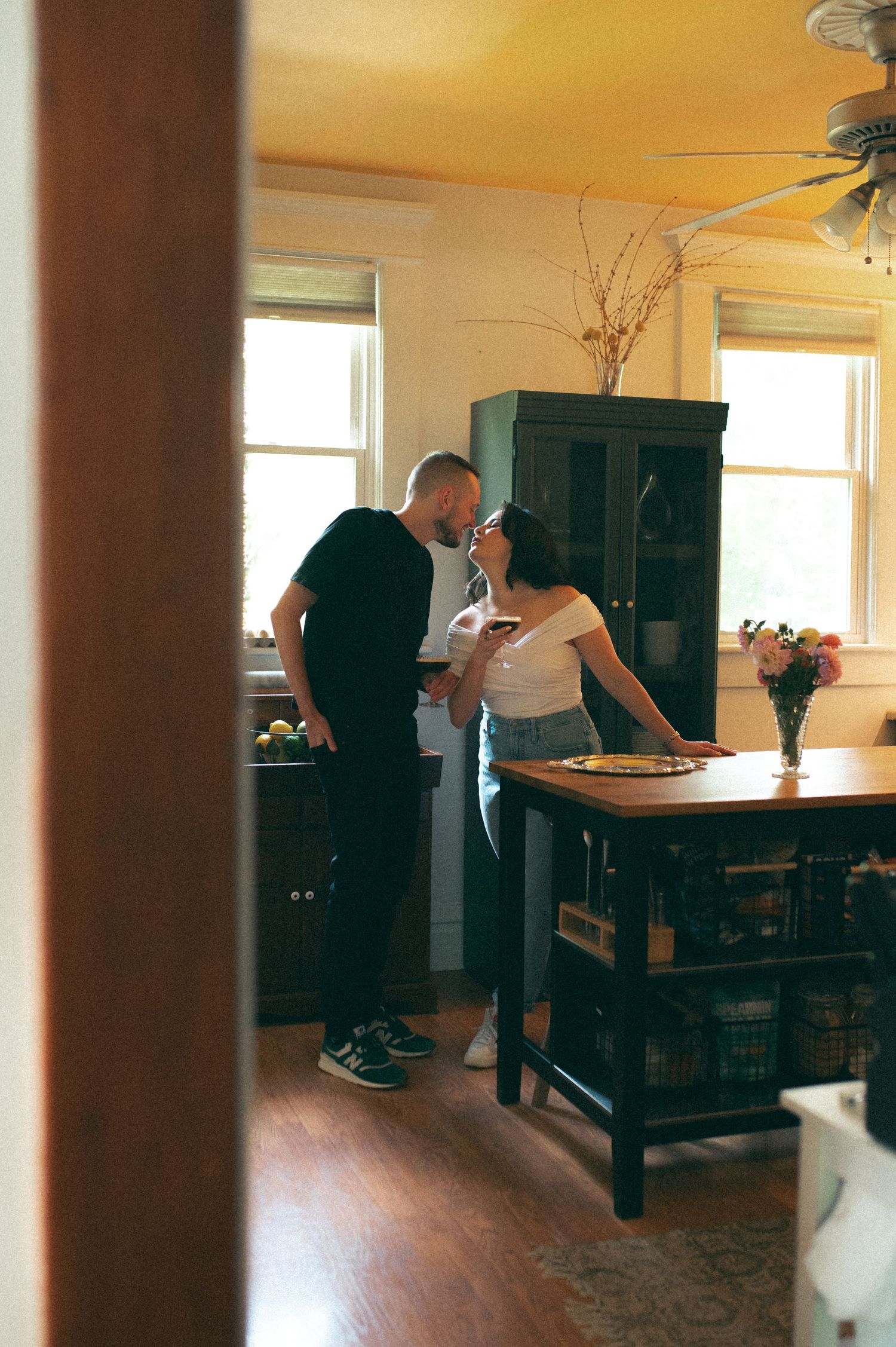 A candid moment between two people in a warm, vintage-style kitchen.