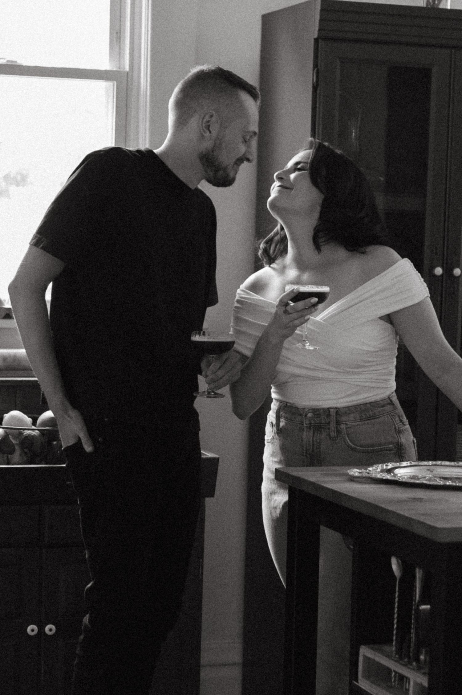 A tender moment captured in black and white between two people sharing drinks.