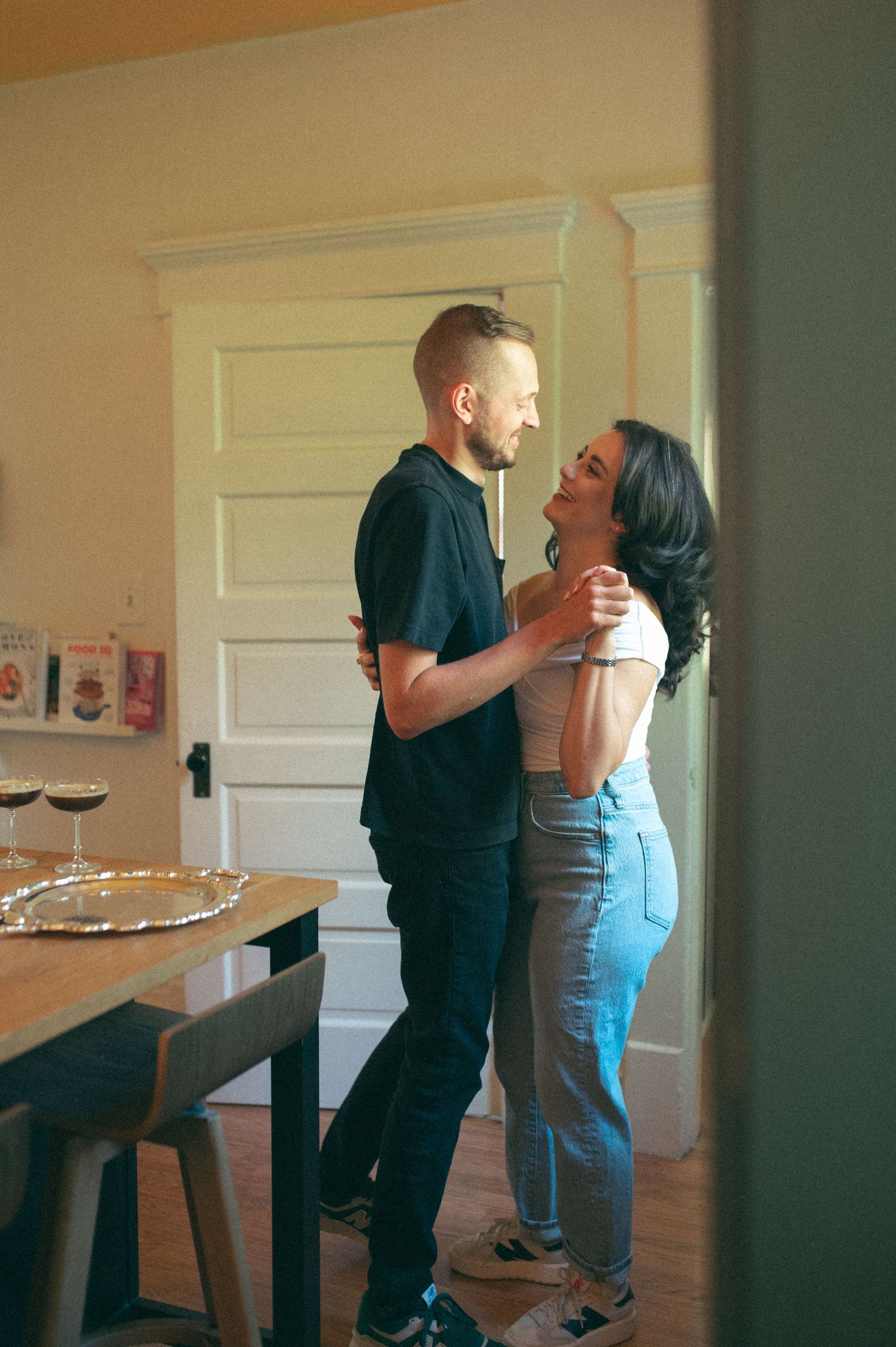 A joyful moment captured between two people in a bright dining room with white walls.