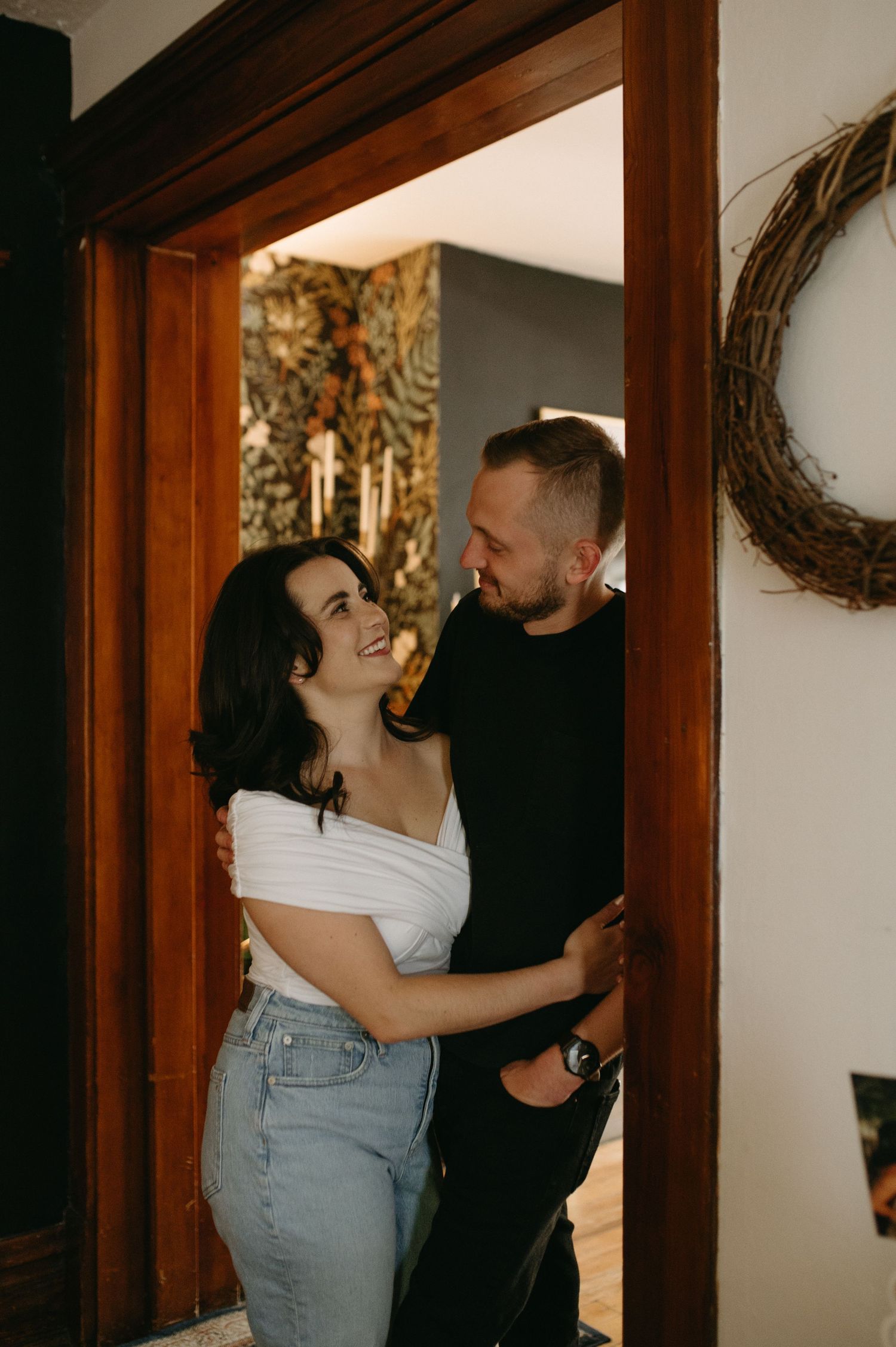 Intimate moment shared between a couple framed by wooden doorway with decorative wreath.