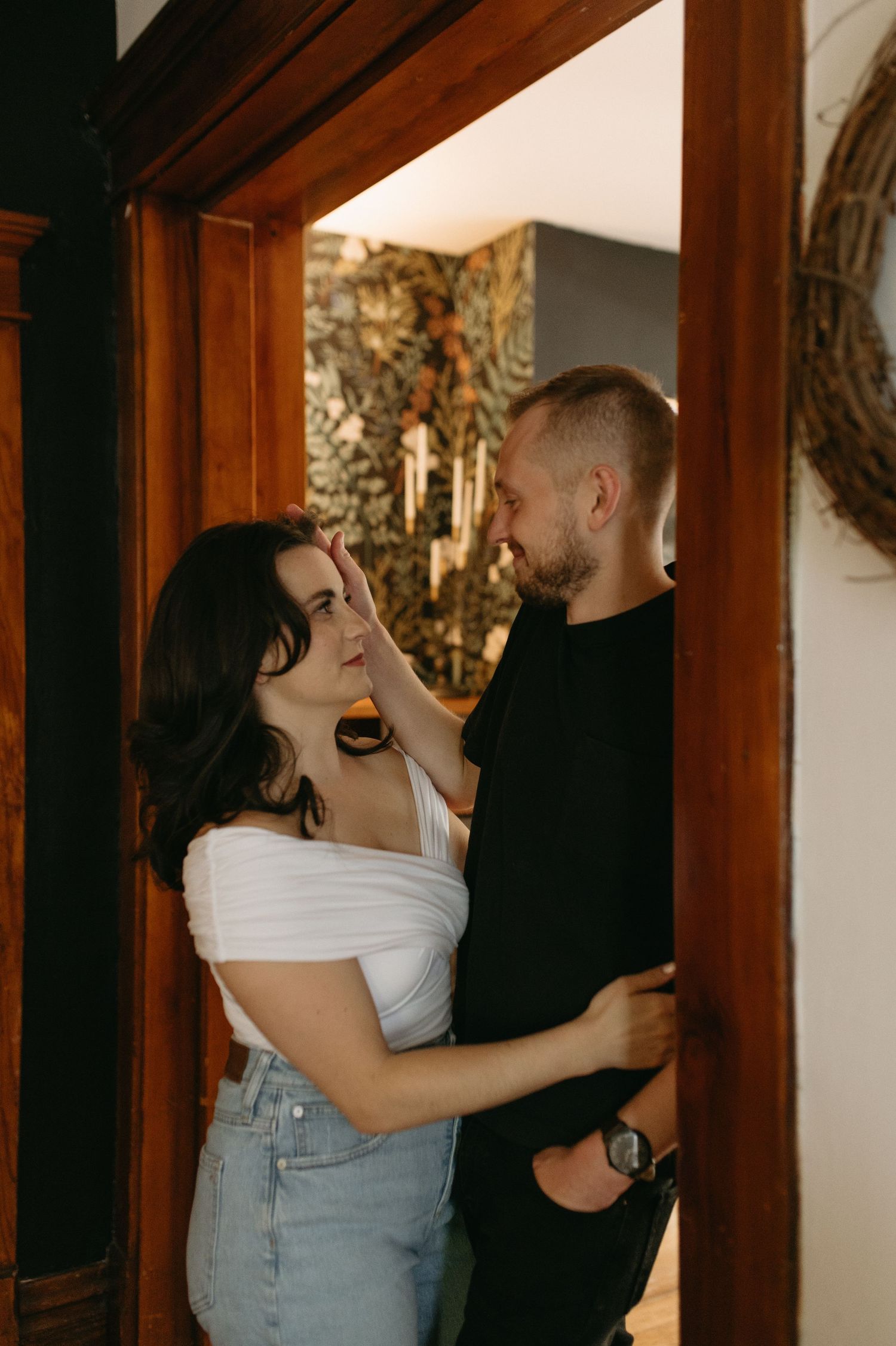 Candid moment of laughter and embrace in front of a doorway with vintage wallpaper.