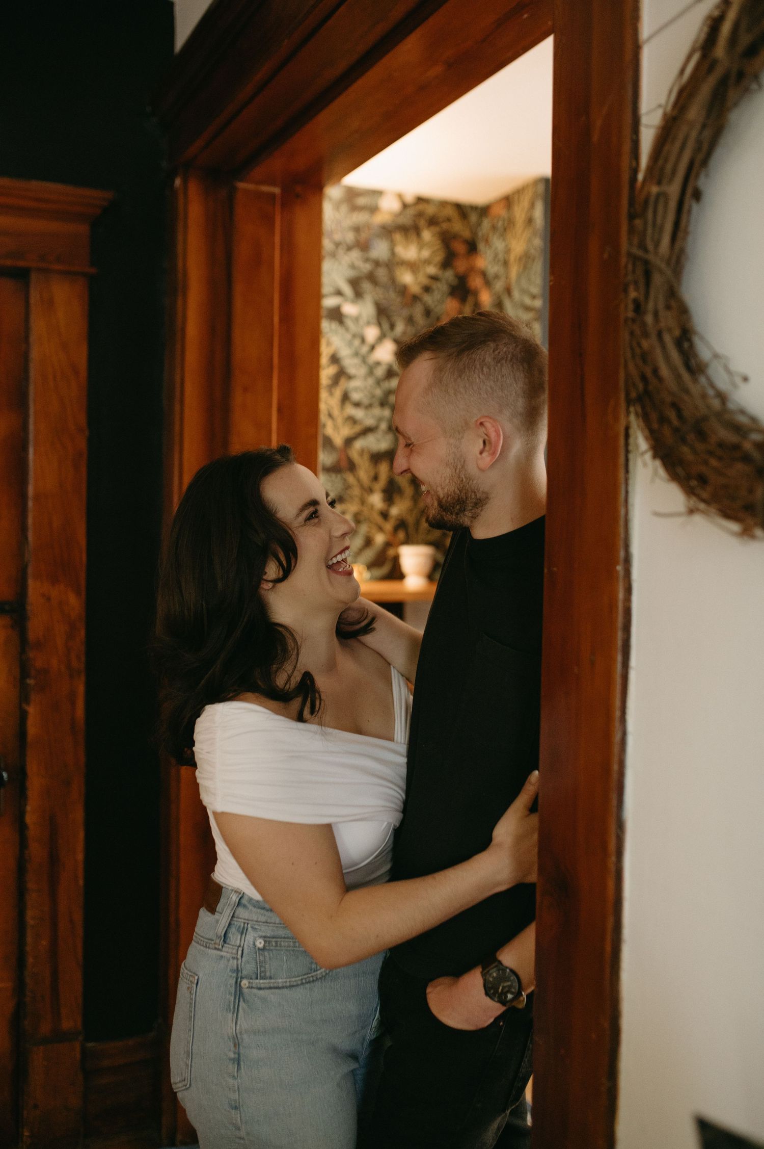 Joyful couple sharing an intimate moment in a doorway with warm wooden trim.