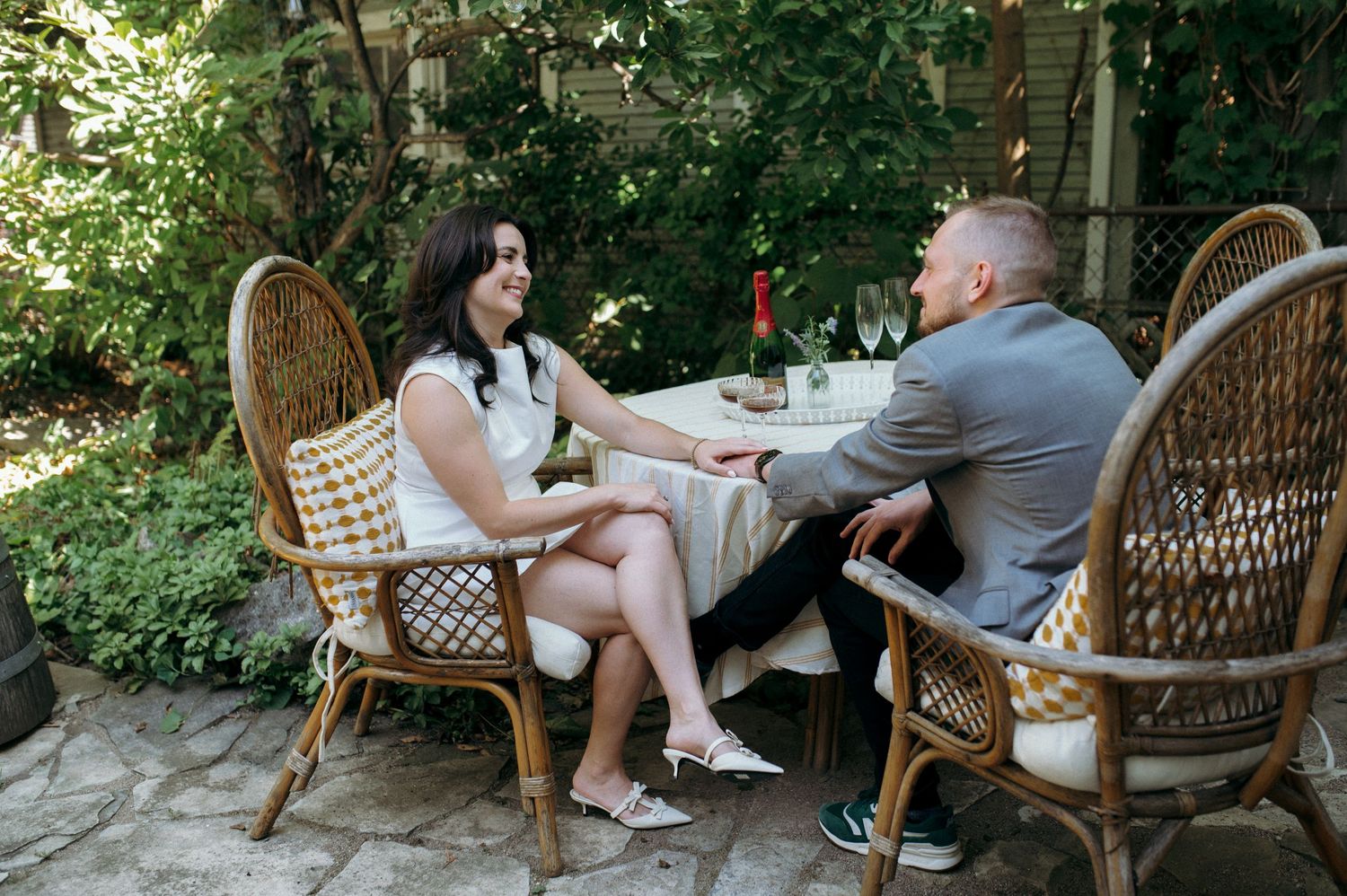 A couple sharing an intimate moment at an outdoor table surrounded by natural greenery.