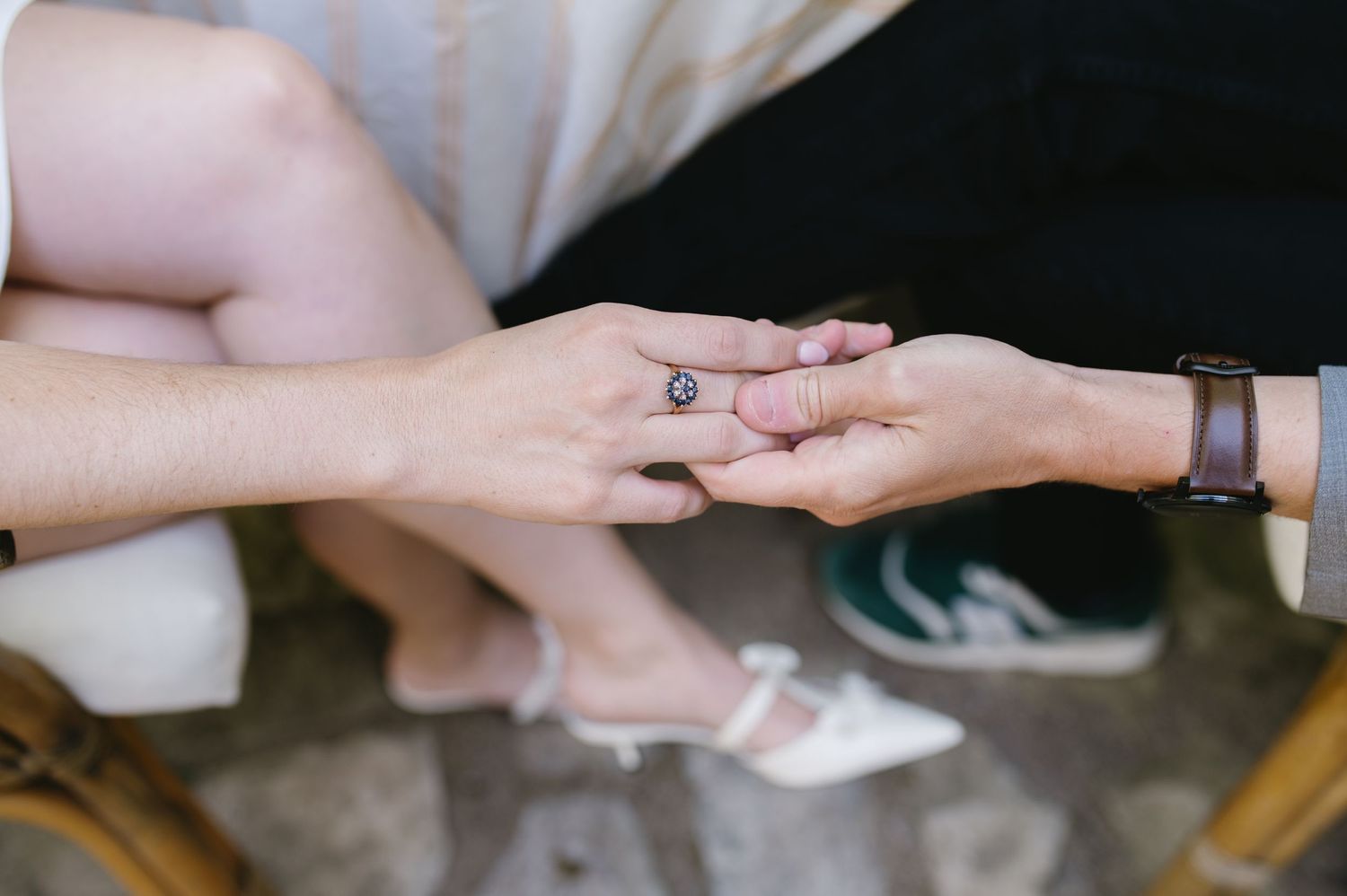 Close-up of hands touching during a romantic engagement moment.