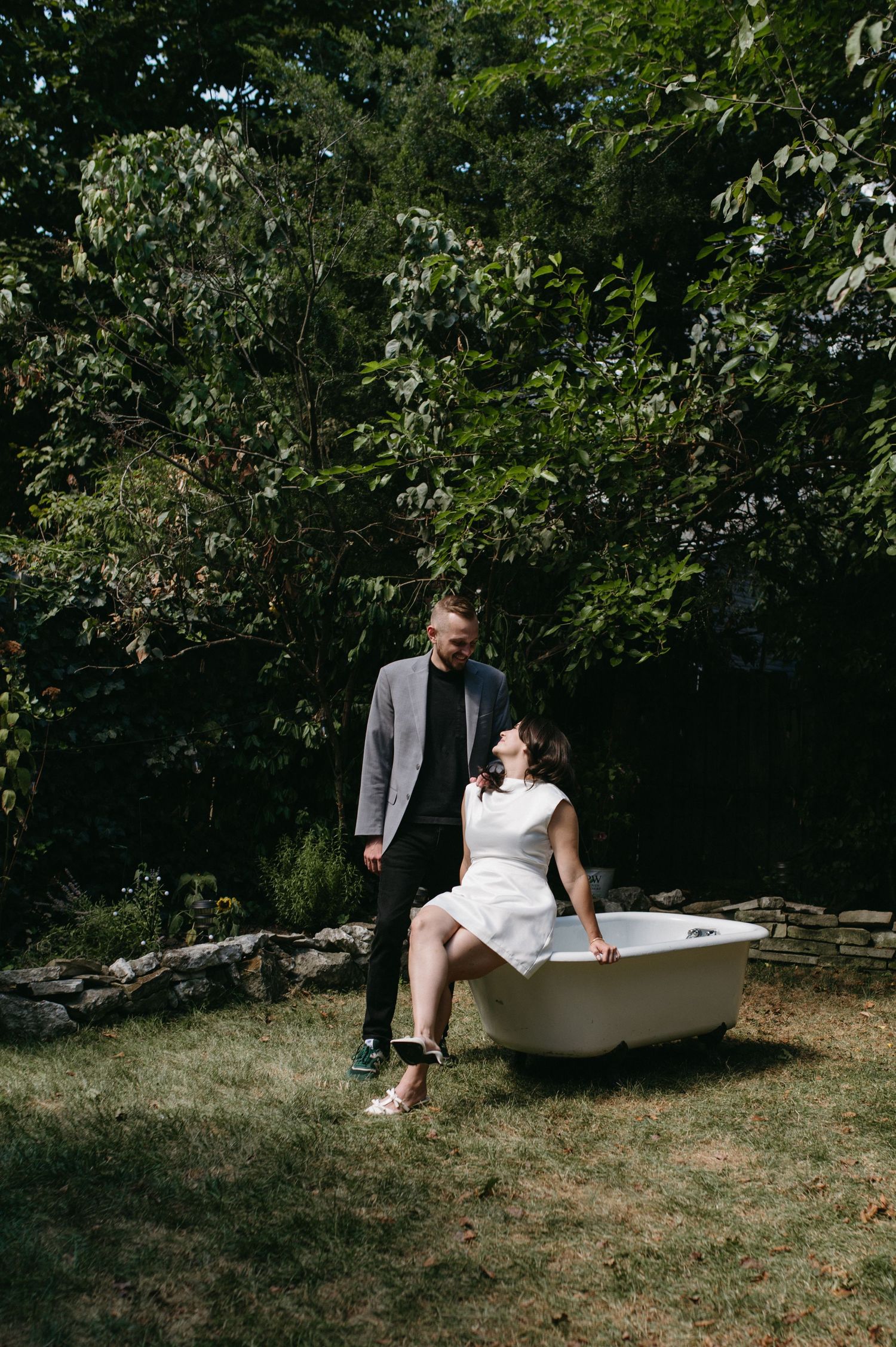 A couple posing together in a garden setting with a vintage bathtub.