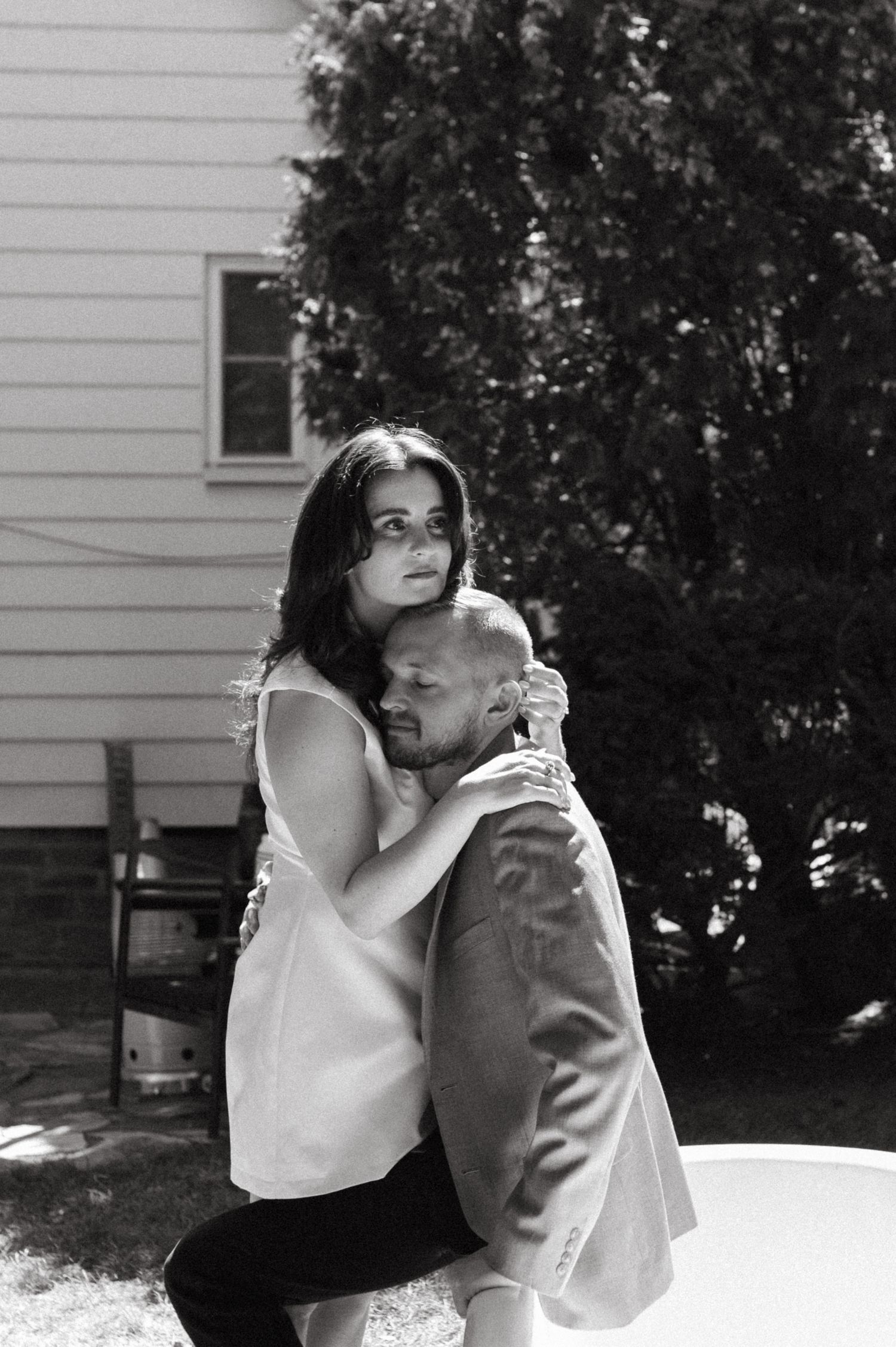 A romantic black and white portrait of a couple embracing outdoors.