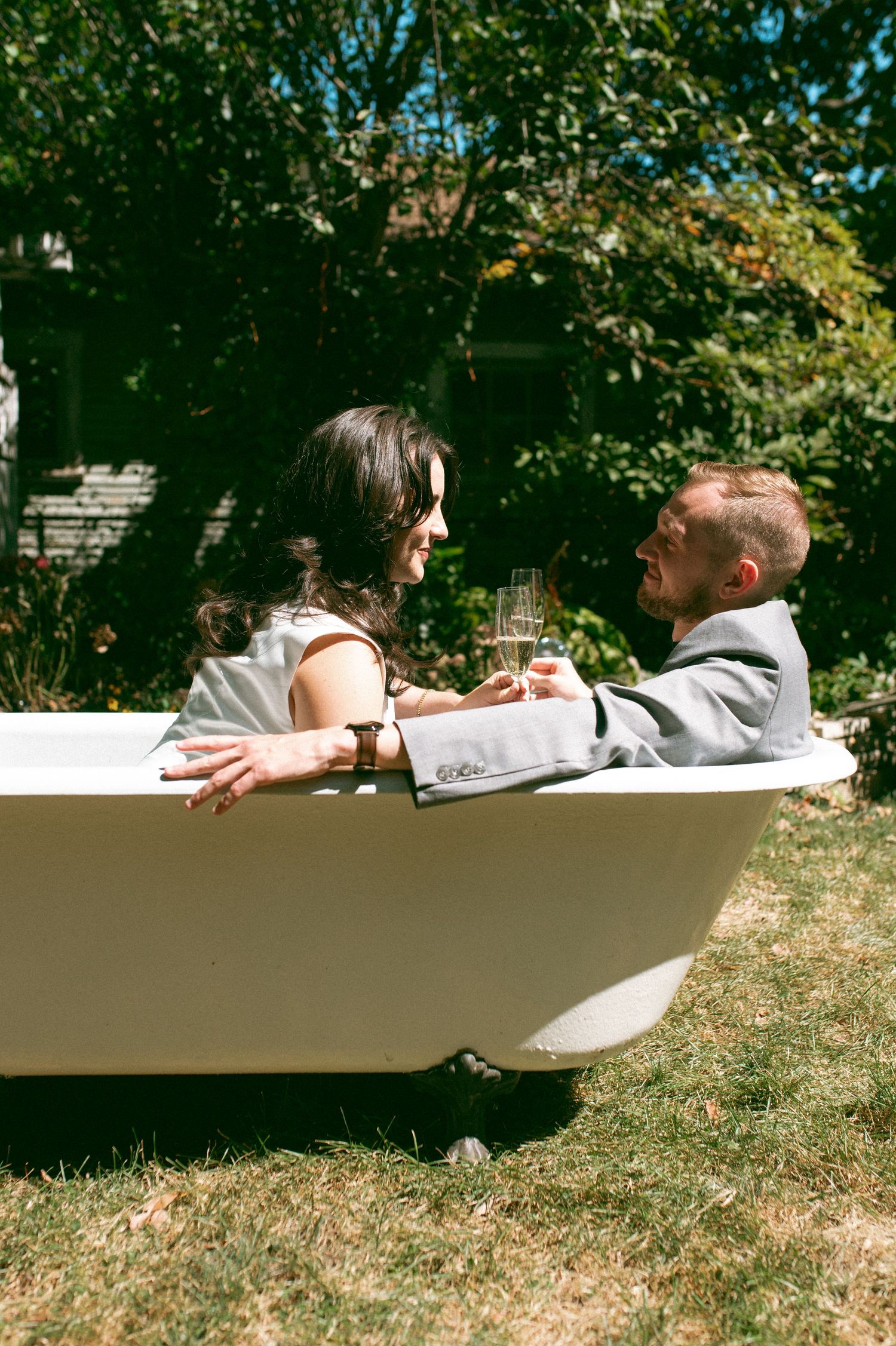Sunny afternoon celebration in outdoor bathtub with champagne glasses.