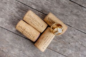 Unionville wine corks with gold wedding rings resting on a rustic wooden surface.