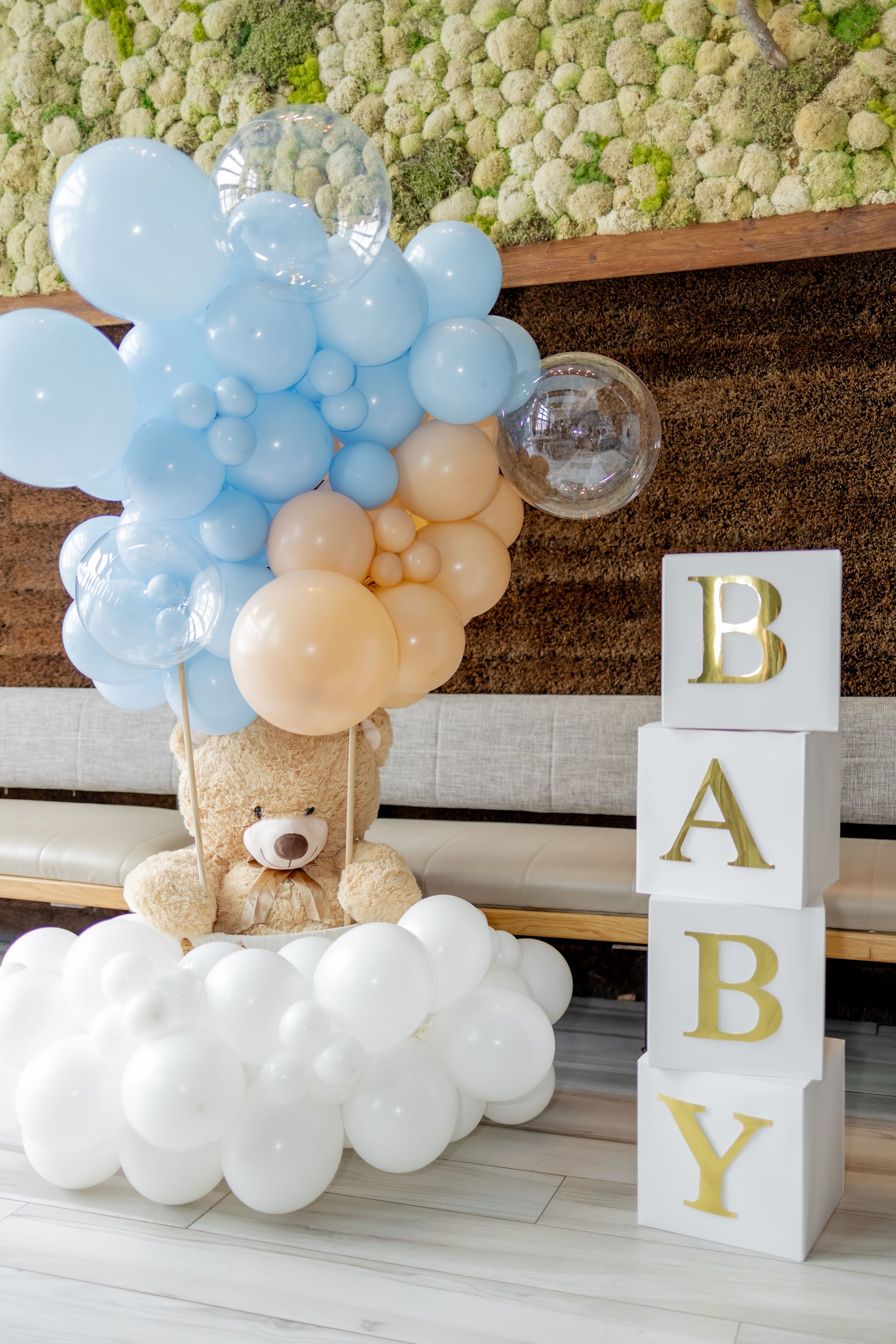 Baby shower decoration with blue and gold balloon arch, teddy bear, and stacked BABY letter boxes at W Hotel in Hoboken, NJ.