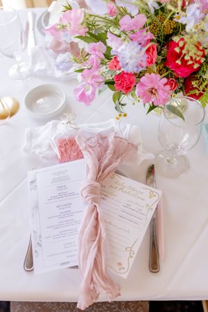 Elegant baby shower table setting with pink floral centerpiece, blush napkins, and personalized menu cards in Long Branch, NJ.