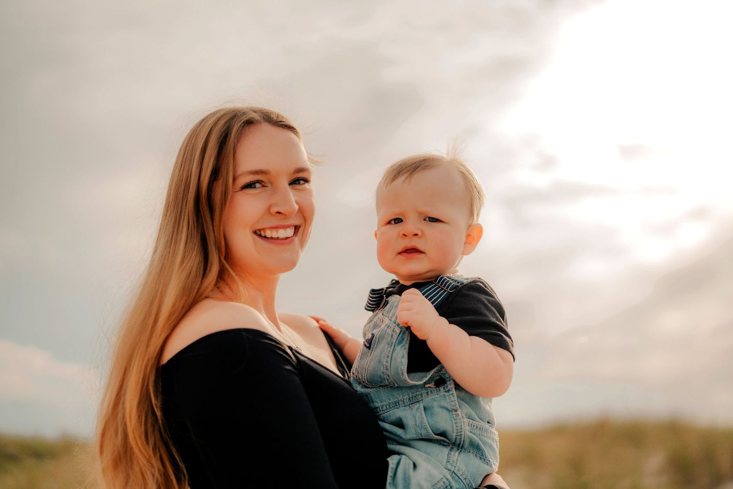 A mother and baby share joyful moments together while playing outdoors during golden hour.