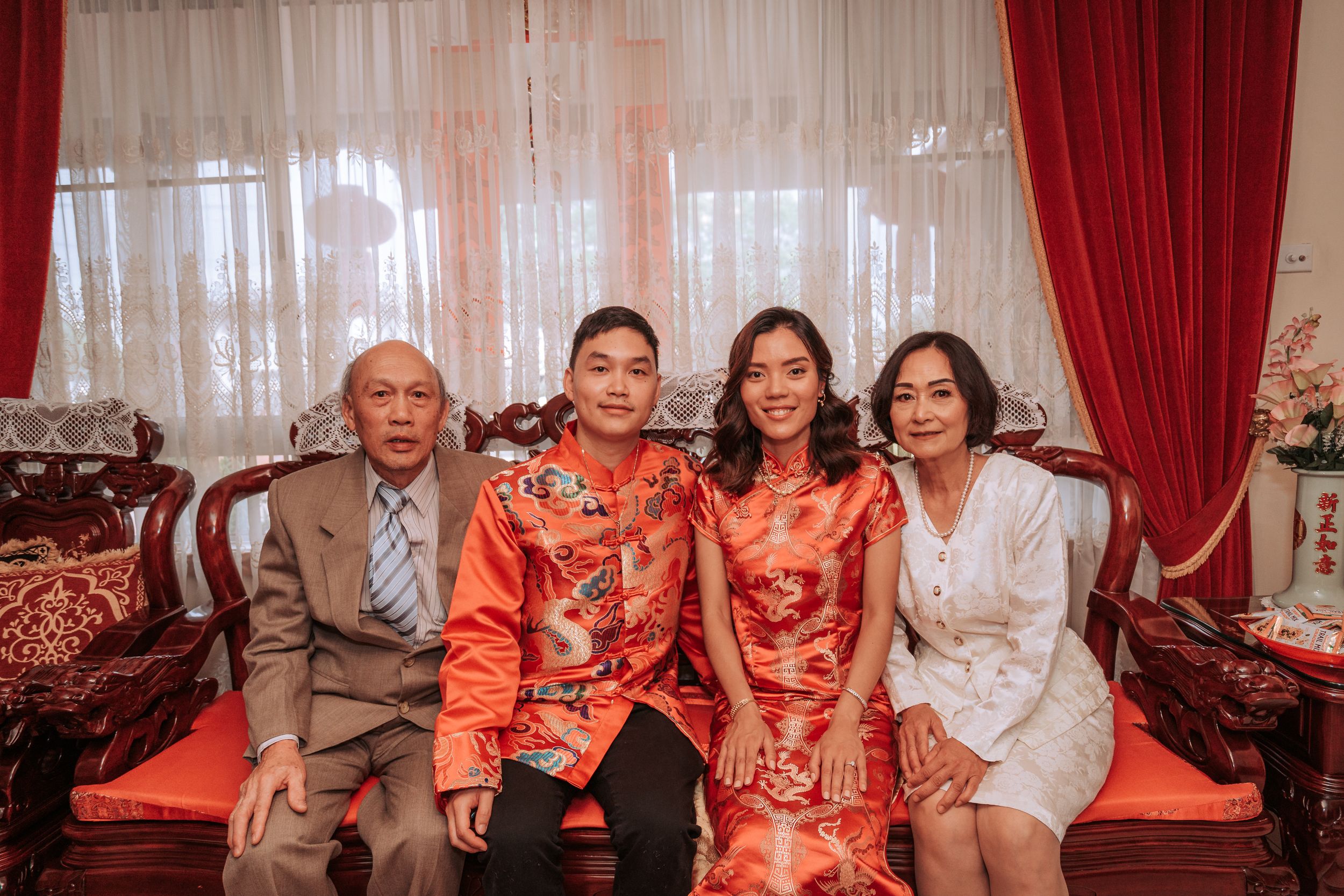 Family group photo featuring traditional red Chinese wedding attire and formal dress.