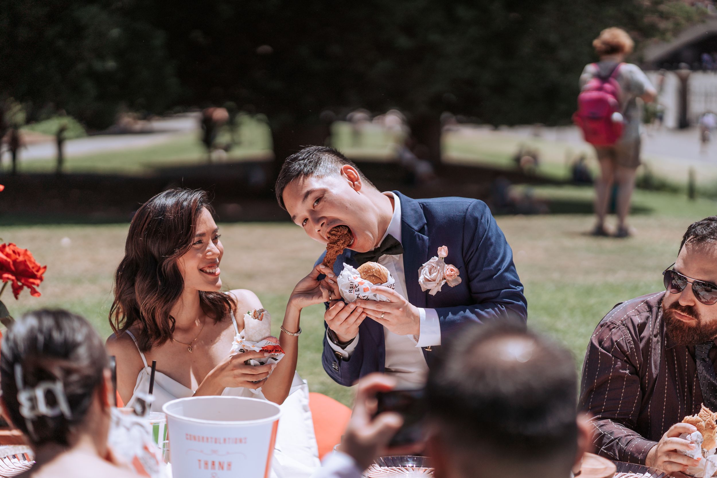 Joyful moment captured during outdoor wedding reception with guests sharing food and laughter.