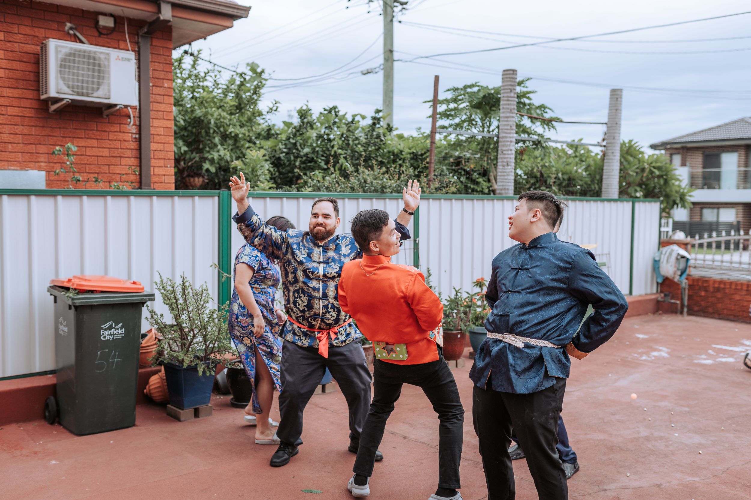 Group performing traditional wedding games or activities in a backyard setting.