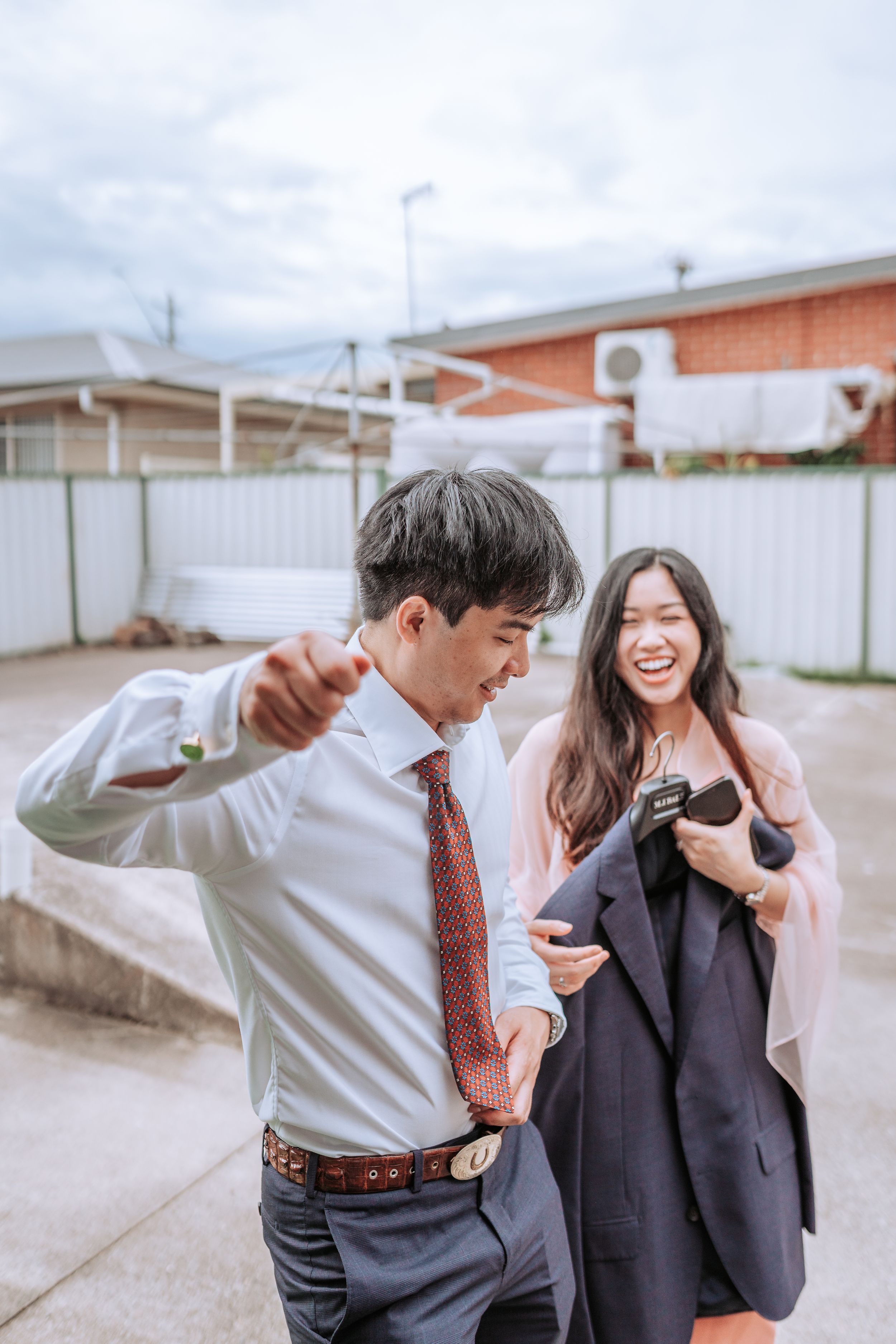 A playful moment captured between a couple outdoors with one doing a dance move.