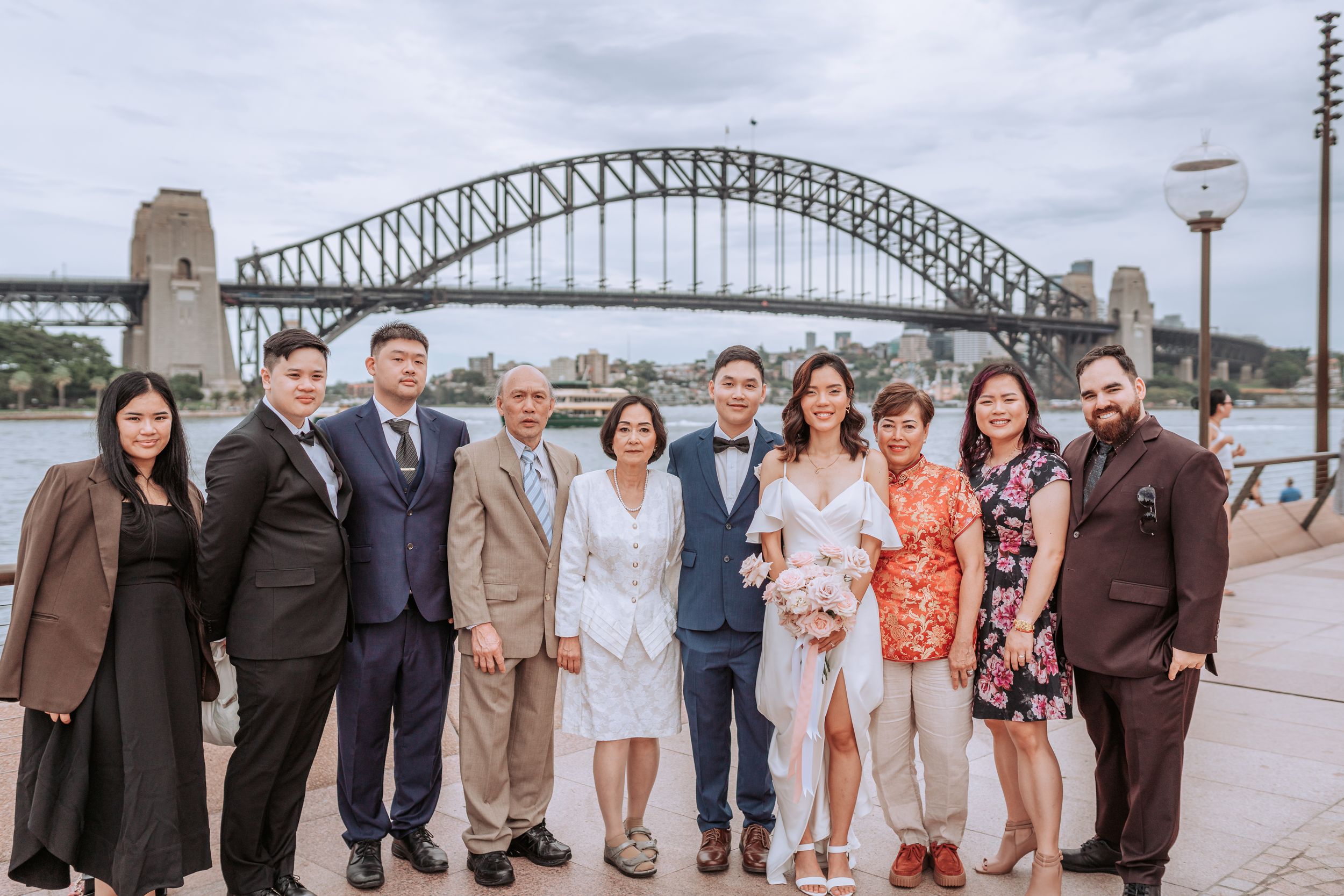 Group photo with Sydney Harbour Bridge in background on cloudy day.