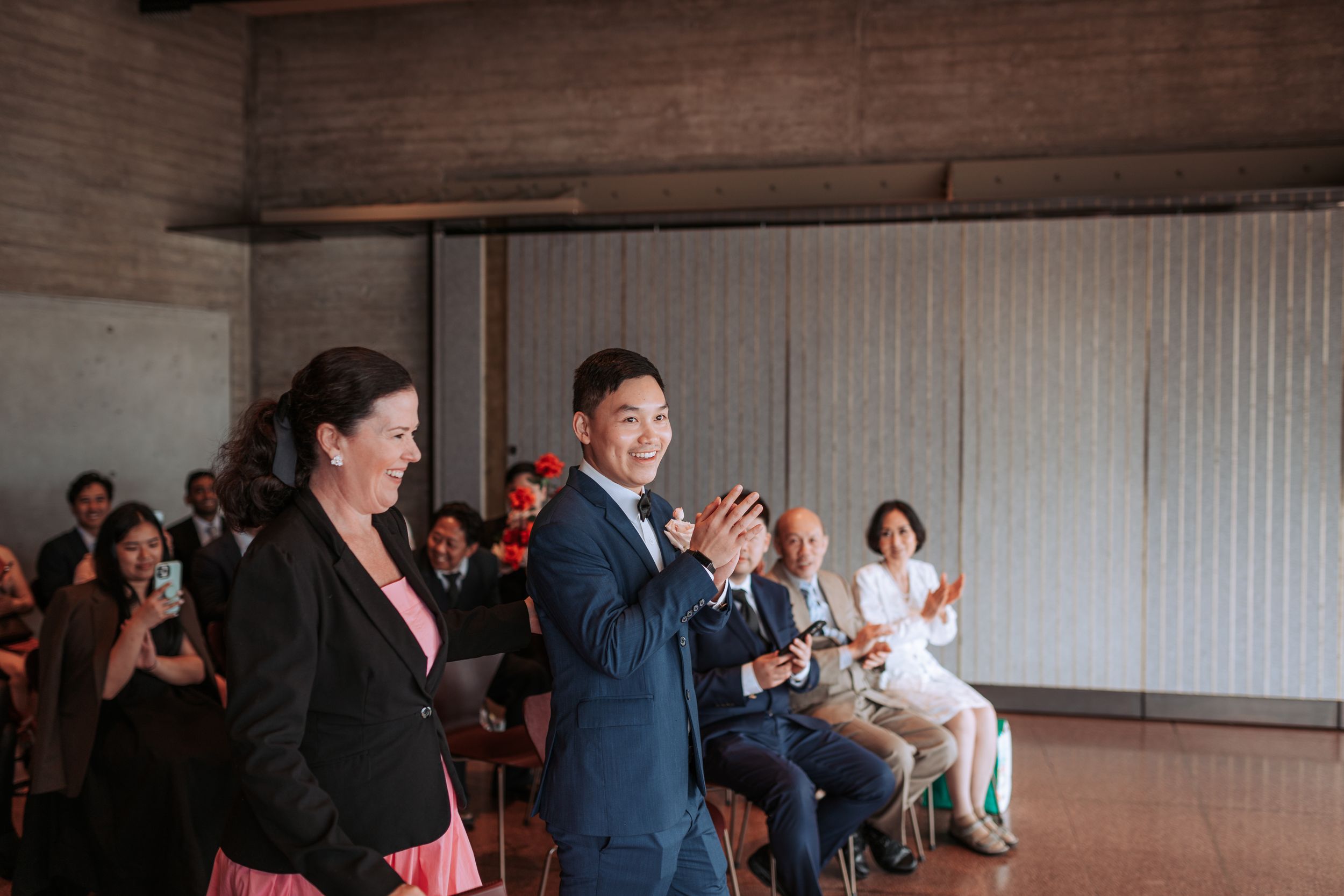 Wedding guests clapping and showing enthusiasm during indoor ceremony.