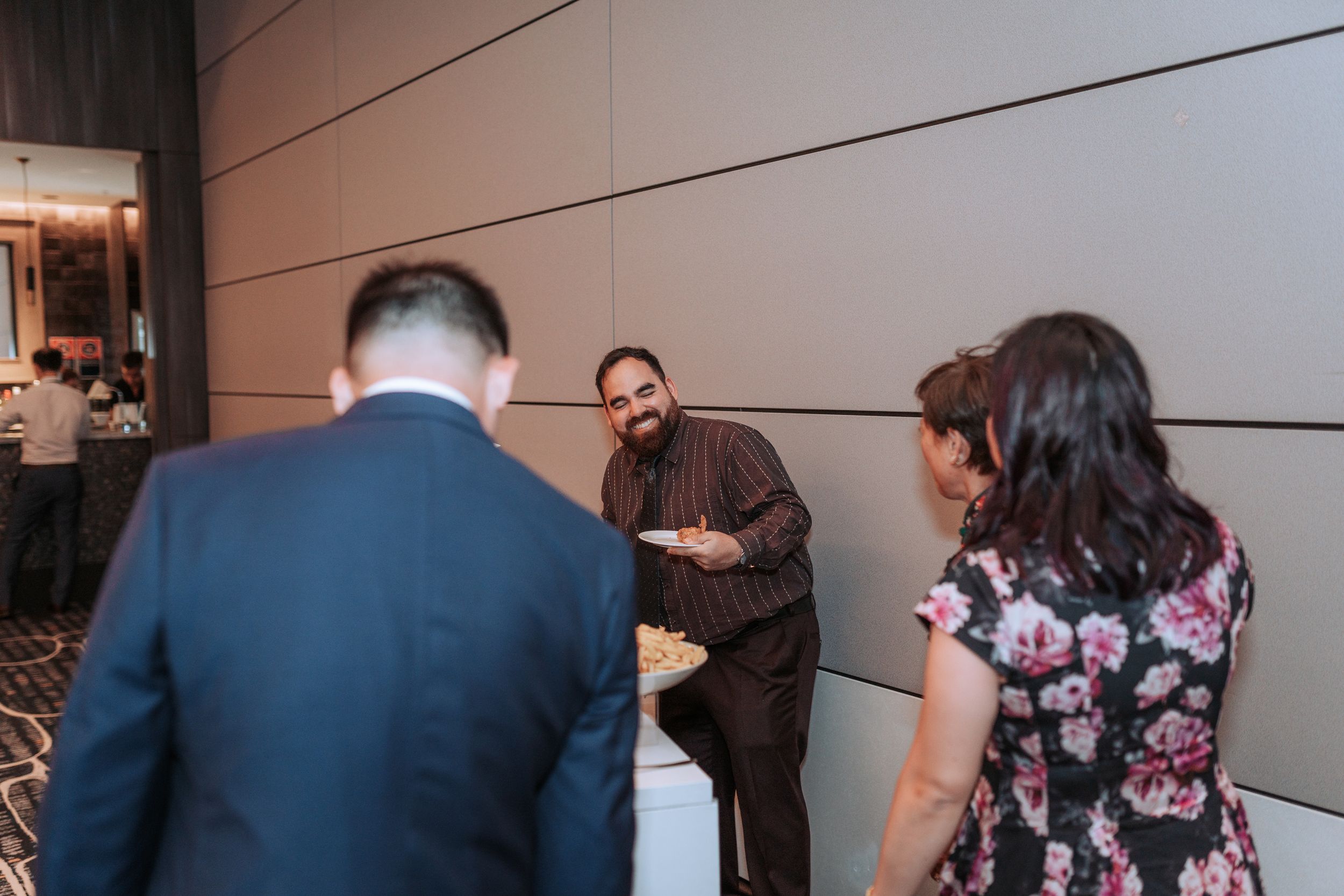 Wedding guests gathered in conversation in a modern hotel hallway.
