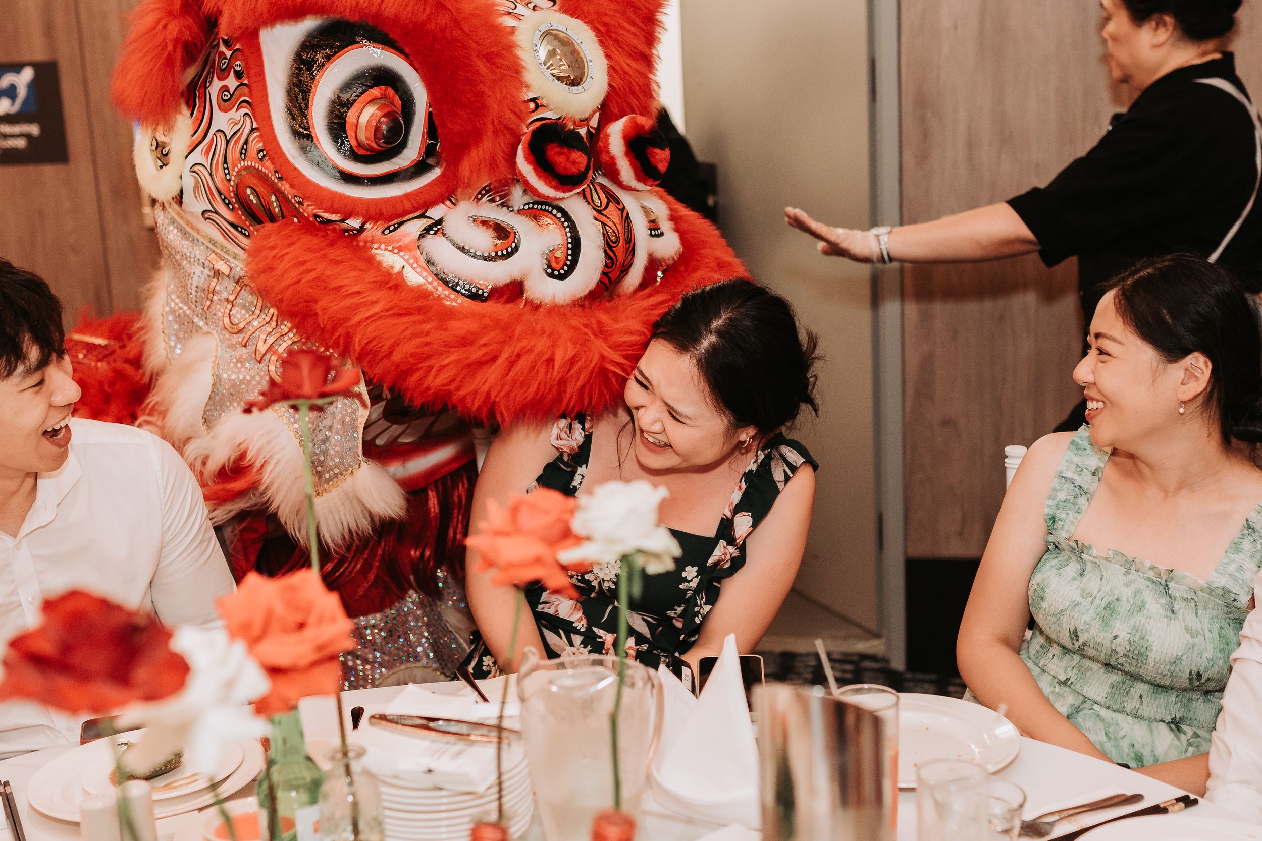 Traditional red and white Chinese lion dance performance entertaining guests at a wedding reception.