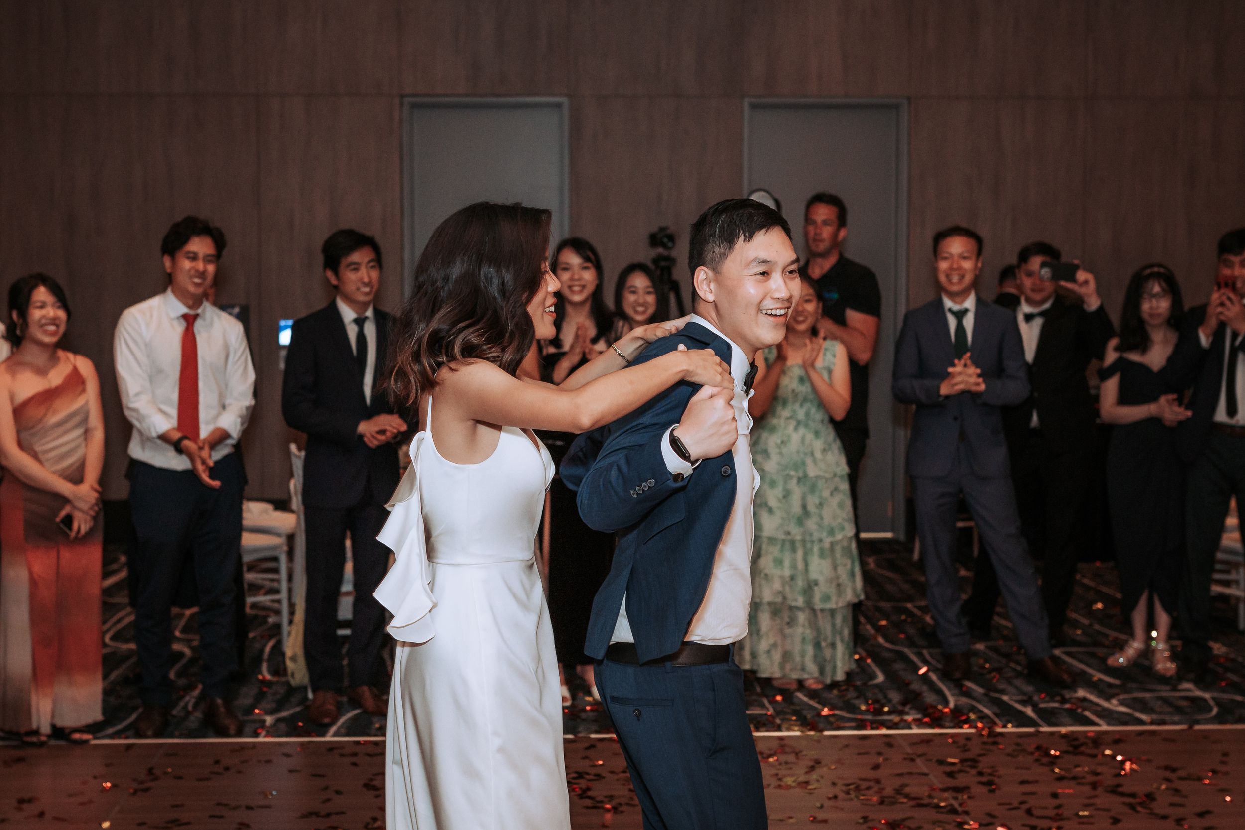 A couple shares their first dance at a wedding reception while guests watch from the sidelines.