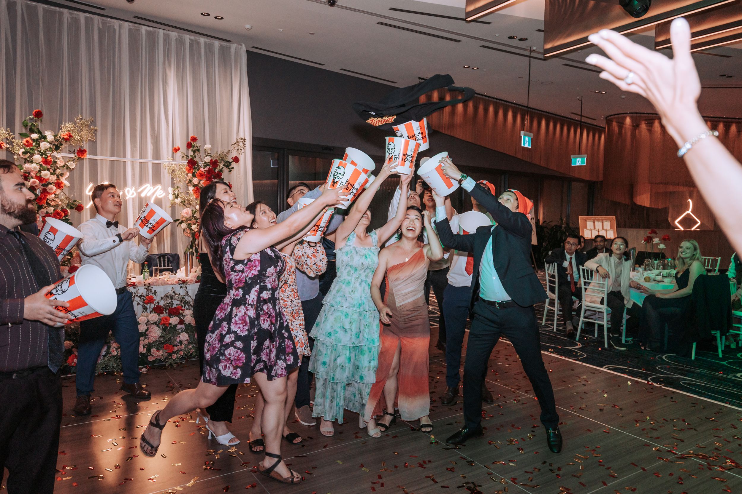Wedding guests dance energetically on the dance floor during a reception celebration.
