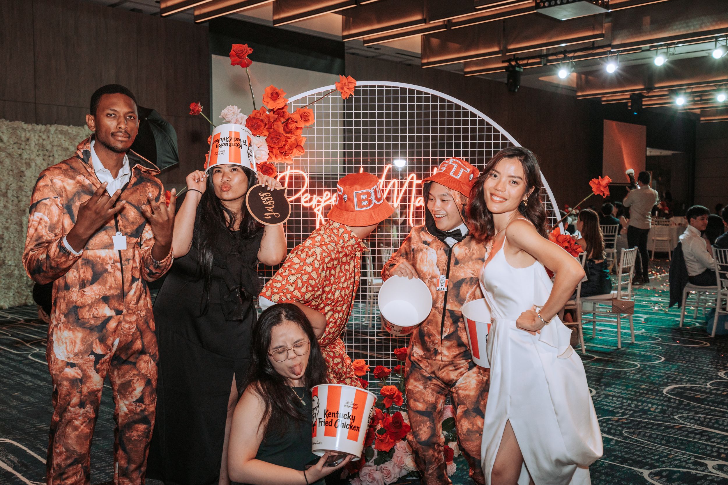 Group poses with party props against a decorative wall at a celebration.
