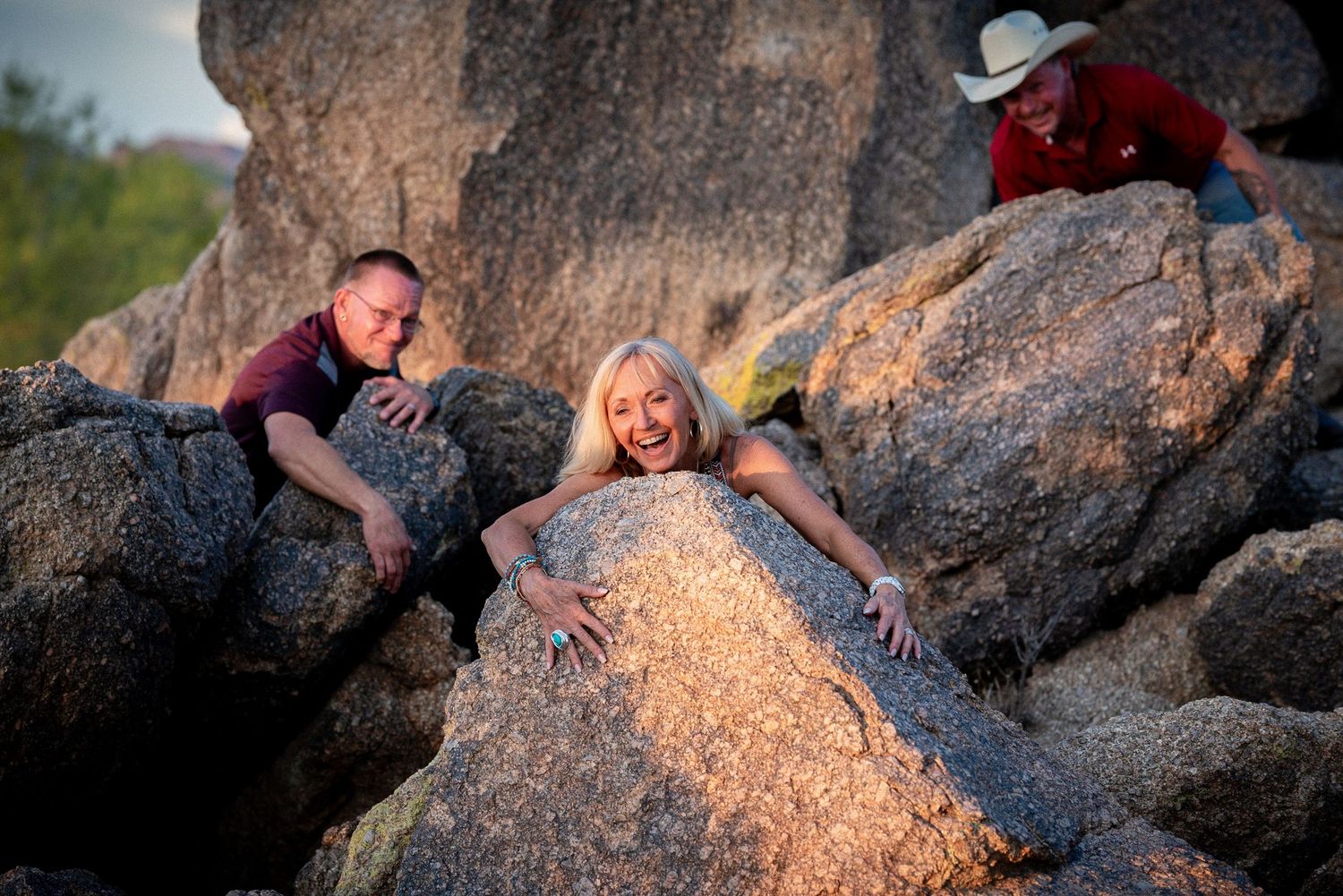 People playfully pose on large rock formations during sunset photography session.