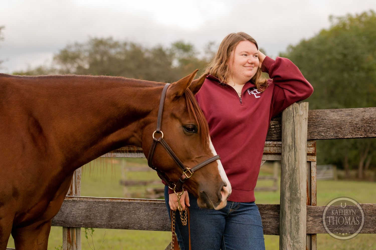 A joyful moment shared between a horse and person in a red sweater by a wooden fence.